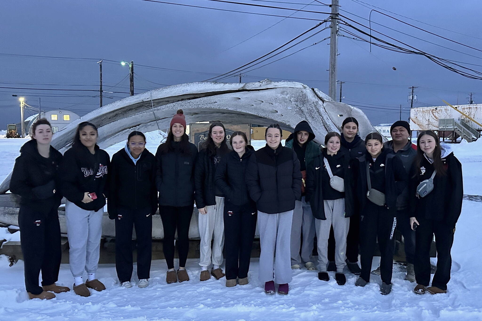 The Juneau-Douglas High School: Yadaa.at Kalé Crimson Bears volleyball team pose for a photo in Utqiagvik, formerly known as Barrow. From left are senior Evelyn Richards, junior Lavinia Ma’ake, senior Nina Jeter, assistant coach Abby Dean, sophomore Amelia Elfers, juniors Cambry Lockhart, Braith Dihle, Neela Thomas, sophomore June Troxel, junior Natalia Harris, sophomore Leila Cooper, assistant coach Mark Ibias and sophomore Braith Dihle. (Courtesy photo)