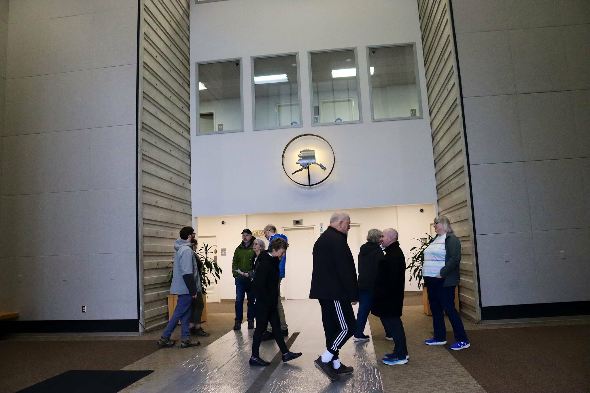 Juneau Assembly members and other visitors gather in the entrance lobby of the Michael J. Burns Building on Monday, April 8, 2024, as part of their on-site tour of potential locations for a new City Hall. (Mark Sabbatini / Juneau Empire file photo)