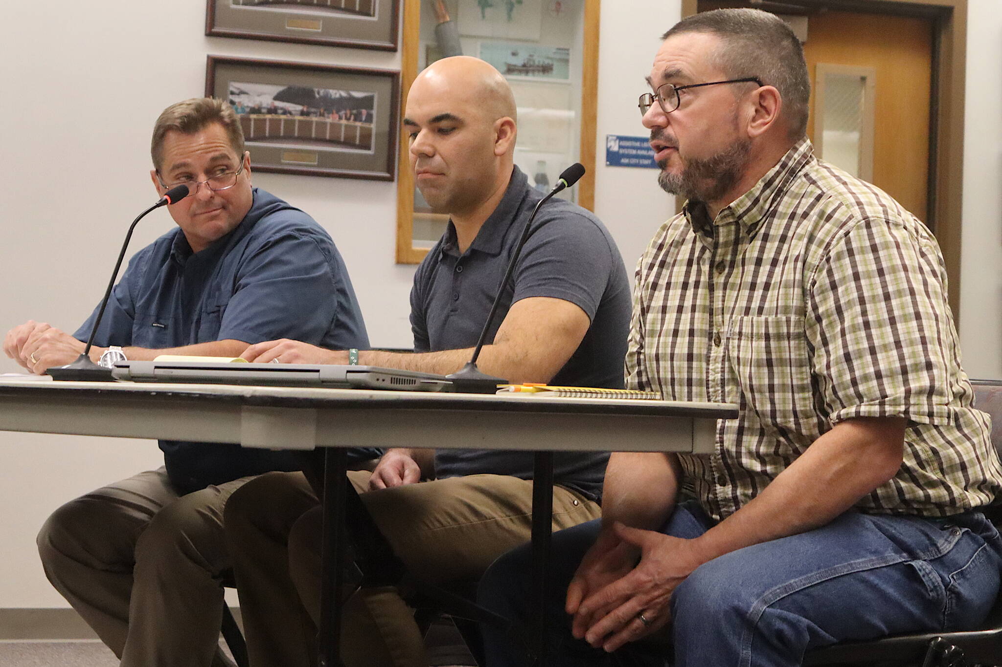 Dan Allard (left) and Philip Martinez (center) from the U.S. Army Corps of Engineers listen to John Bohan, an engineer with the City and Borough of Juneau, as the three men provide information about flood barriers to Juneau Assembly members during a meeting Monday night at City Hall. (Mark Sabbatini / Juneau Empire)