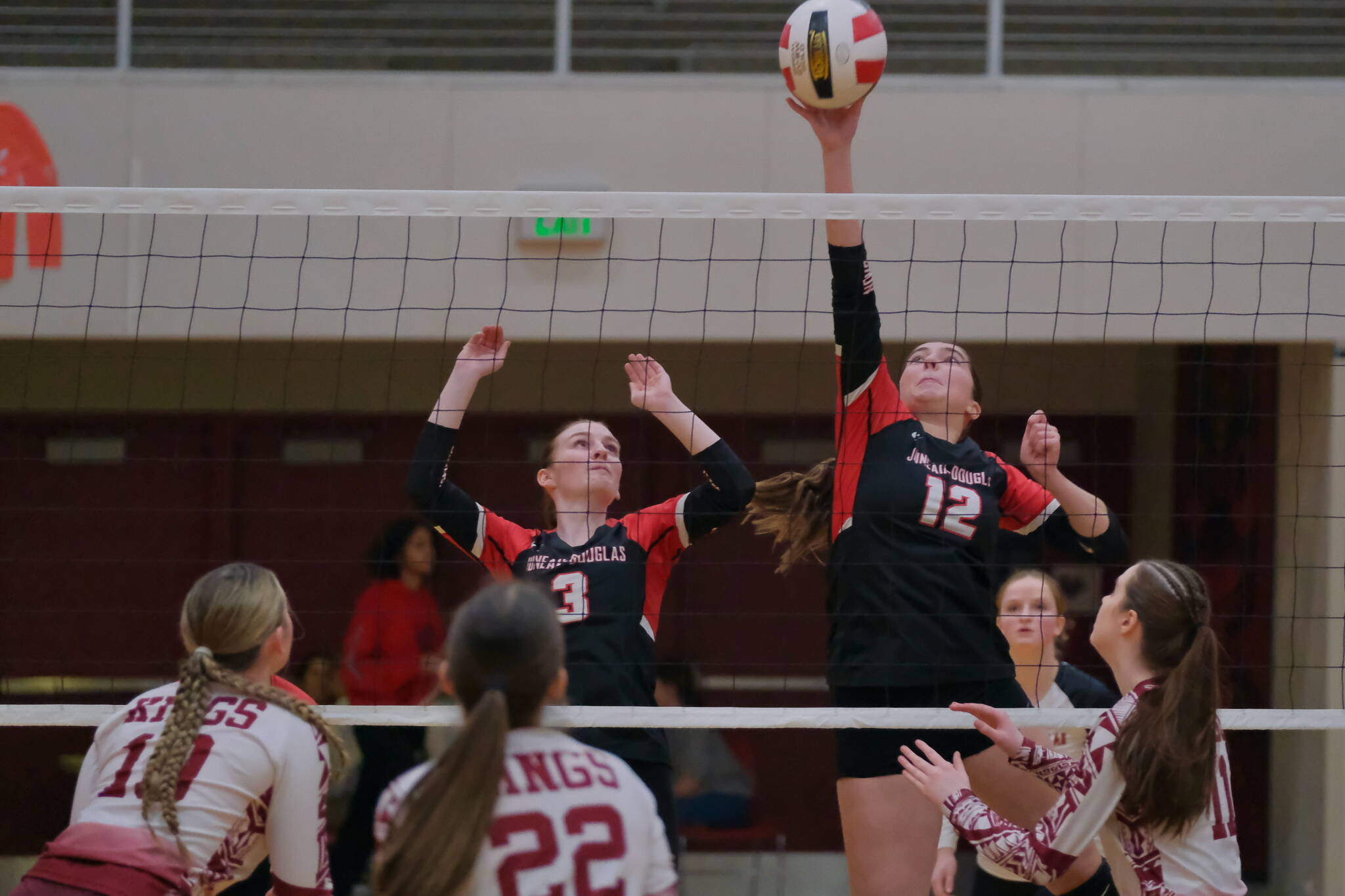 Juneau-Douglas High School: Yadaa.at Kalé junior Neela Thomas (12) tips a shot against Ketchikan as senior teammate Tatum Billings and Kayhi junior Genevieve Halbert (10) and sophomores Mariah Pechay-Austin (22) and Avah Bittle (11) react during the Crimson Bears 20-25, 25-9, 25-11, 25-18 match win Friday during the Region V Volleyball Championships at Juneau’s George Houston Gymnasium. (Klas Stolpe / Juneau Empire)