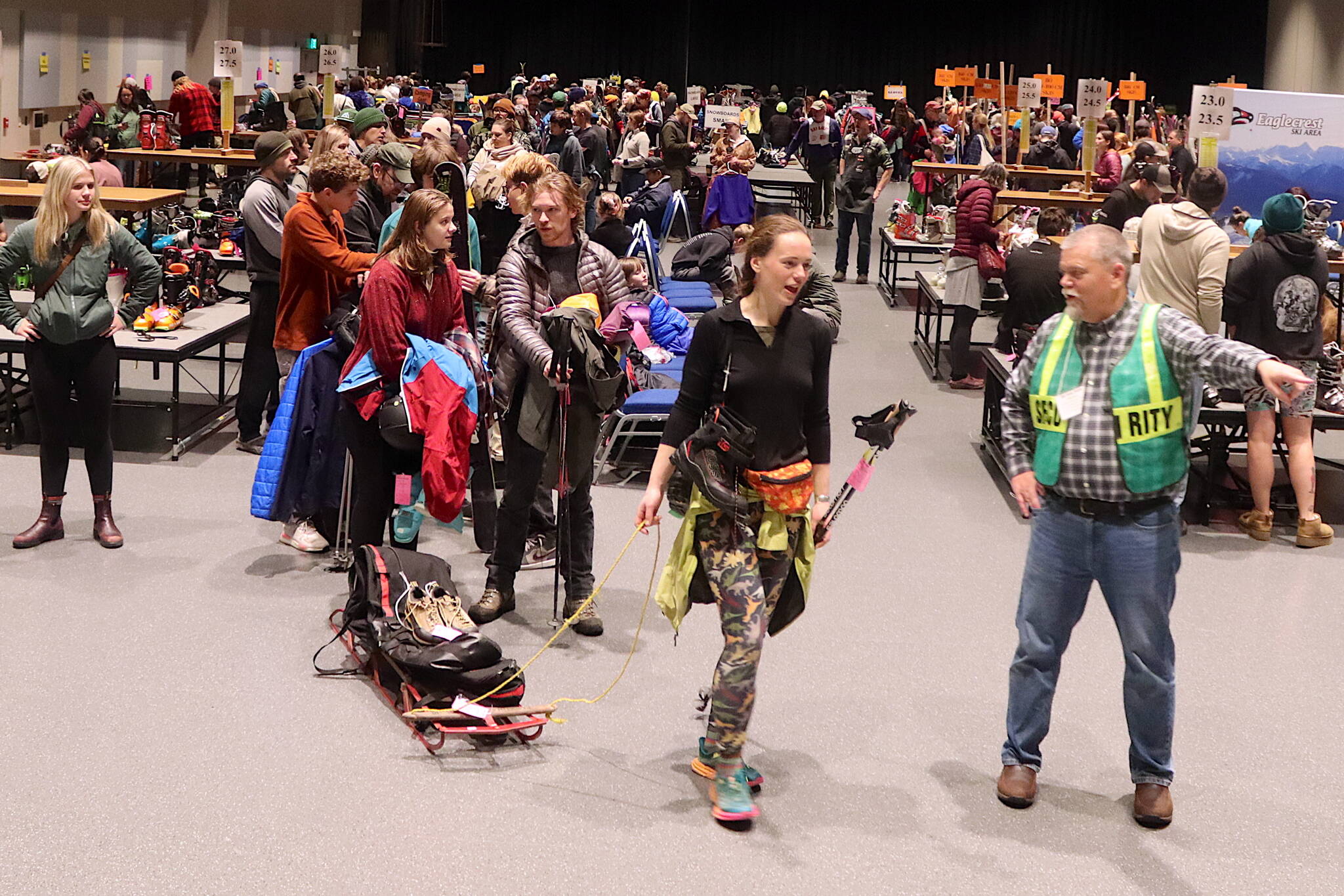 Eaglecrest Ski Area Board President Mike Satre (right) points Megan Behnke toward a checkout person during the annual Juneau Ski Sale at Centennial Hall on Saturday. (Mark Sabbatini / Juneau Empire)