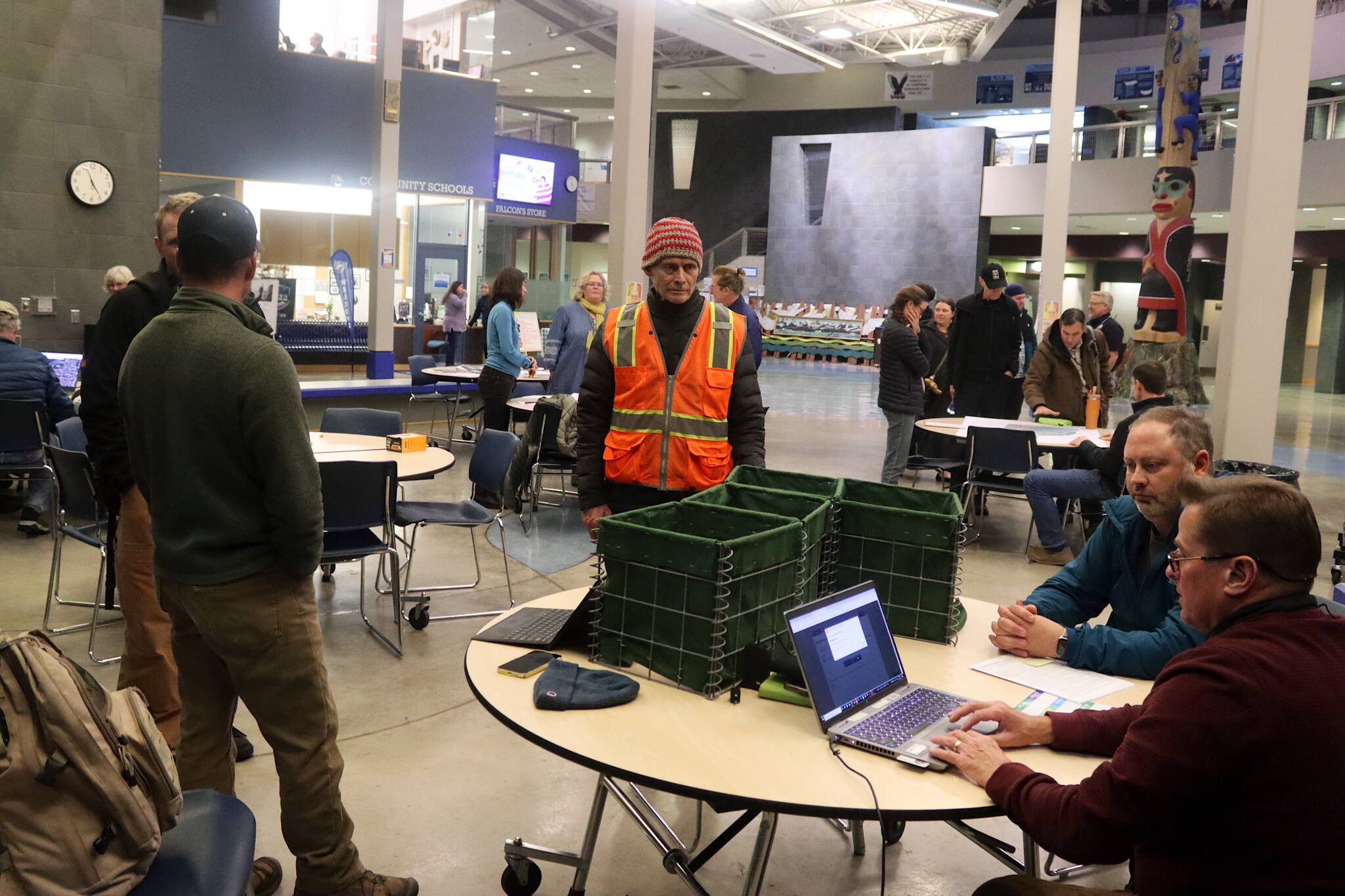 Dan Allard (right), a flood fighting expert for the U.S. Army Corps of Engineers, explains how Hesco barriers function at a table where miniature replicas of the three-foot square and four-foot high barriers are displayed during an open house Thursday evening at Thunder Mountain Middle School to discuss flood prevention options in Juneau. (Mark Sabbatini / Juneau Empire)