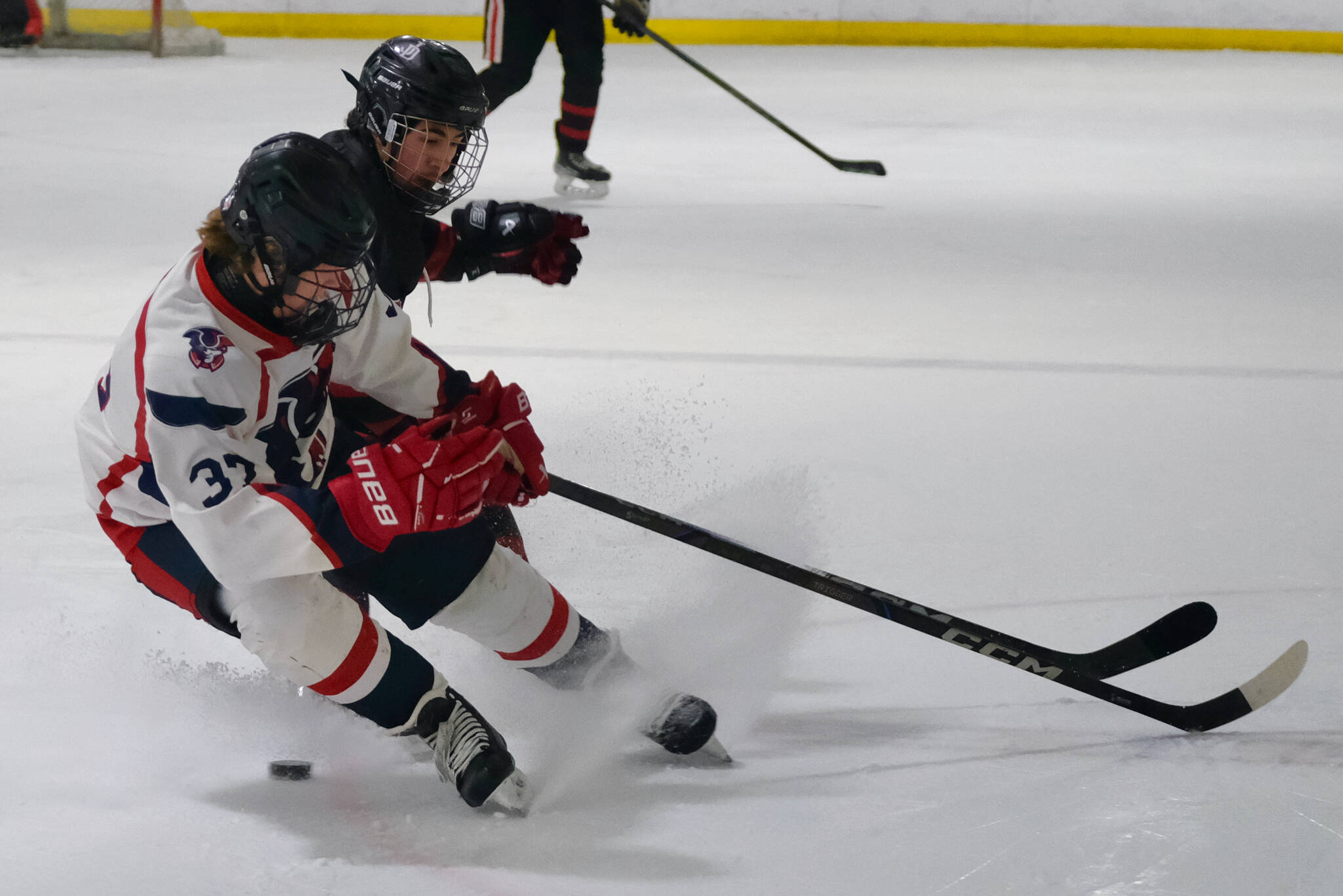 Juneau-Douglas High School: Yadaa.at Kalé senior Emilio Holbrook battles for a puck with North Pole junior Hunter Simons (37) during the Crimson Bears’ 5-2 loss to the Patriots on Saturday at the Treadwell Ice Arena. (Klas Stolpe / Juneau Empire)