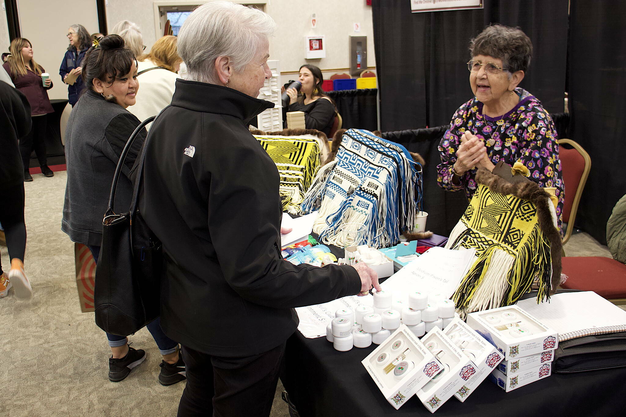 Ann Stepetin (left) and Marion Dau (center) talk to Pauline Duncan about her woven aprons and other items for sale at the Indigenous Artists and Vendors Holiday Market on Friday, Nov. 24, 2023 at Elizabeth Peratrovich Hall. (Mark Sabbatini / Juneau Empire file photo)