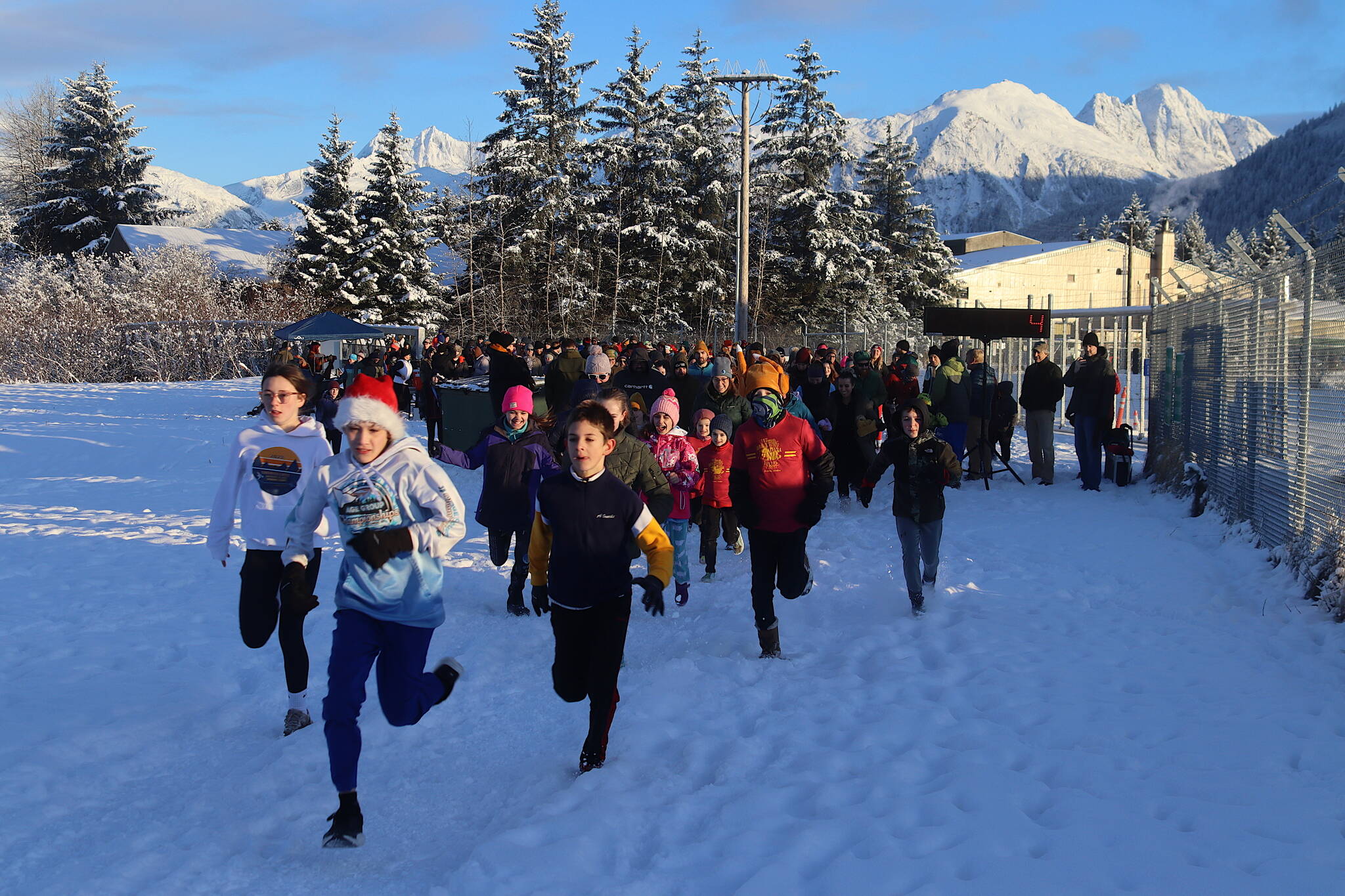 Austin Treston (wearing Santa hat) and Oliver Albrecht, both 11, lead off participants in the mile-long course during the annual Turkey Trot 5K and 1 Mile Fun Run on Thursday along the Airport Dike Trail. (Mark Sabbatini / Juneau Empire)