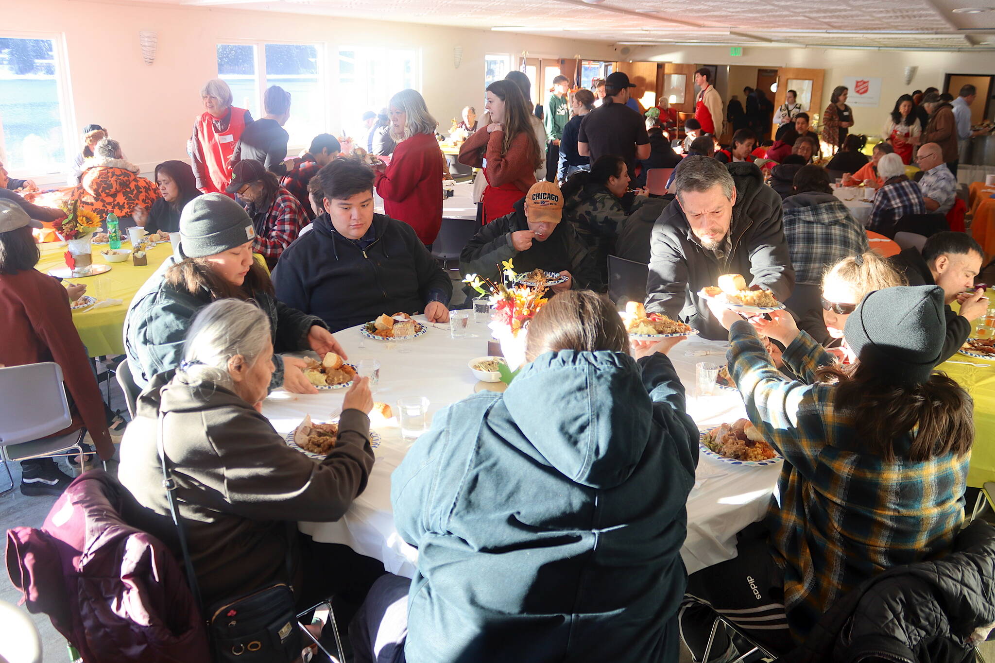 William James (standing) hands plates of Thanksgiving food to family members during a communal holiday meal hosted by The Salvation Army Juneau Corps on Thursday at the Juneau Yacht Club. (Mark Sabbatini / Juneau Empire)