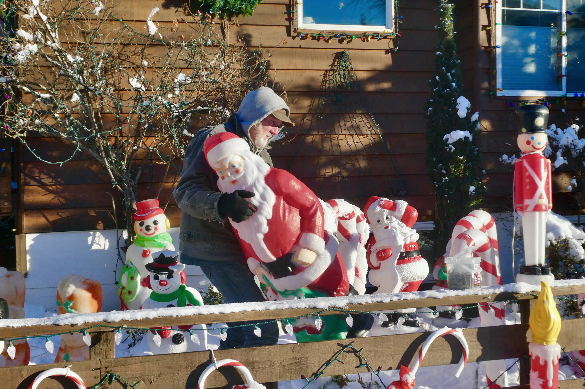 Jeff Campbell moves a Santa figurine into the front yard of his annual Christmas-themed holiday house on West 11th Street in the downtown neighborhood known as The Flats on Thursday, Nov. 28. Campbell begins the decorating after removing Halloween fare and usually turns on the lights in December. Campbell has created this masterpiece annually for over 30 years. Besides Santas, the display includes candy canes, drummer boys, nativity scenes, reindeer and Disney and Winnie the Pooh characters and some of his own creations. He also has thousands of lights and speakers wired to play Christmas music and his electricity bill doubles over the display’s longevity. (Klas Stolpe / Juneau Empire)