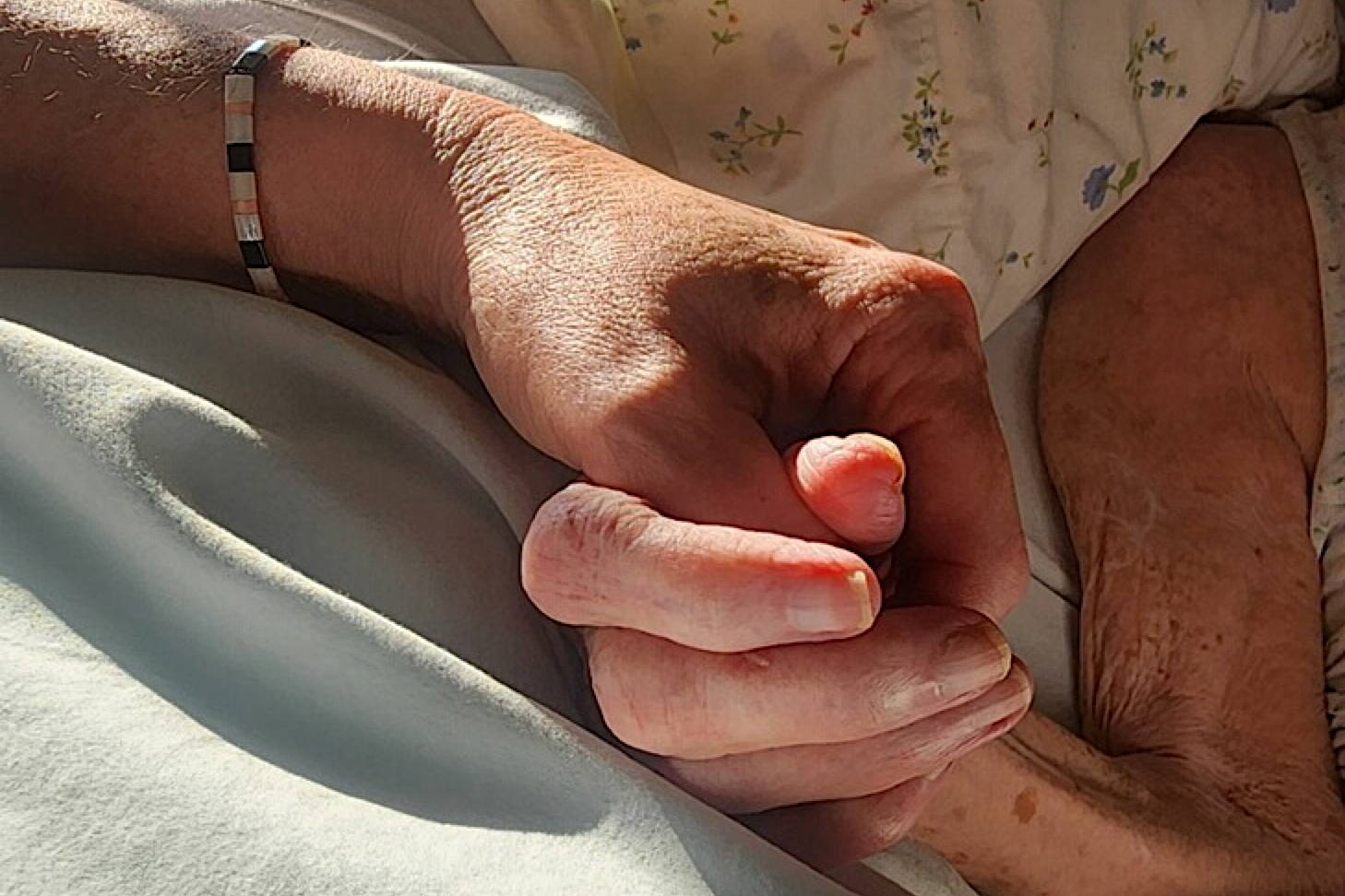 The author holds her mother’s hand two hours before she died. (Photo by Gabriella Hebert)