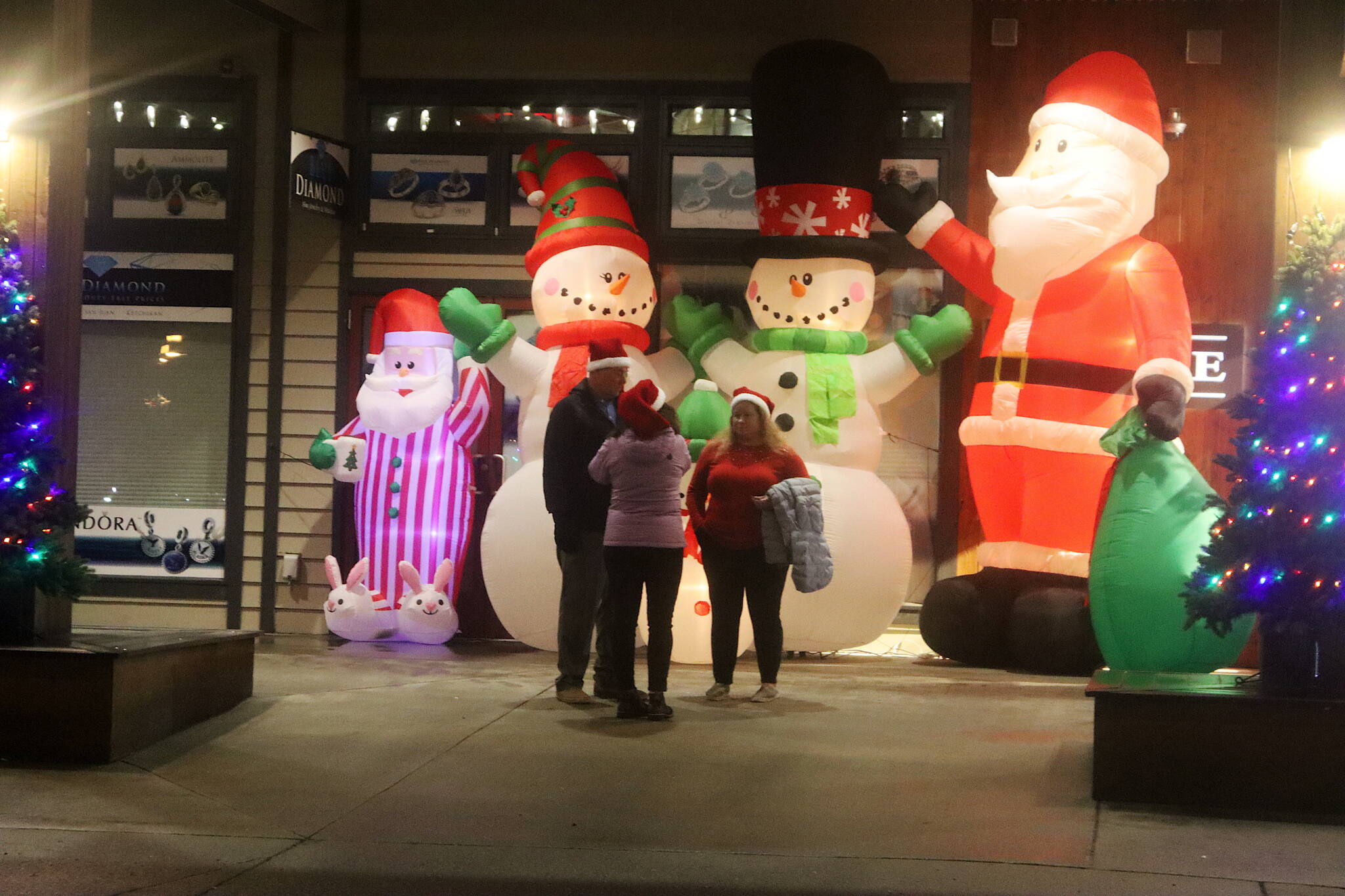 A trio of humans is dwarfed by a quartet of Christmas characters in a storefront on South Franklin Street during Gallery Walk on Friday. (Mark Sabbatini)