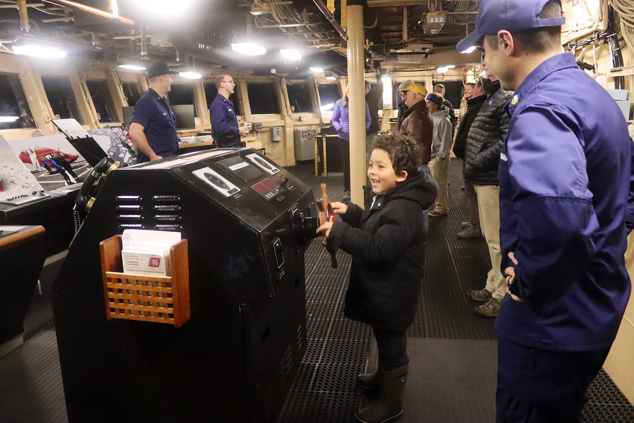 Darius Heumann tries his hand at an old-fashioned steering wheel on the bridge of the U.S. Coast Guard’s Healy icebreaker during a public tour on Friday. (Mark Sabbatini / Juneau Empire)