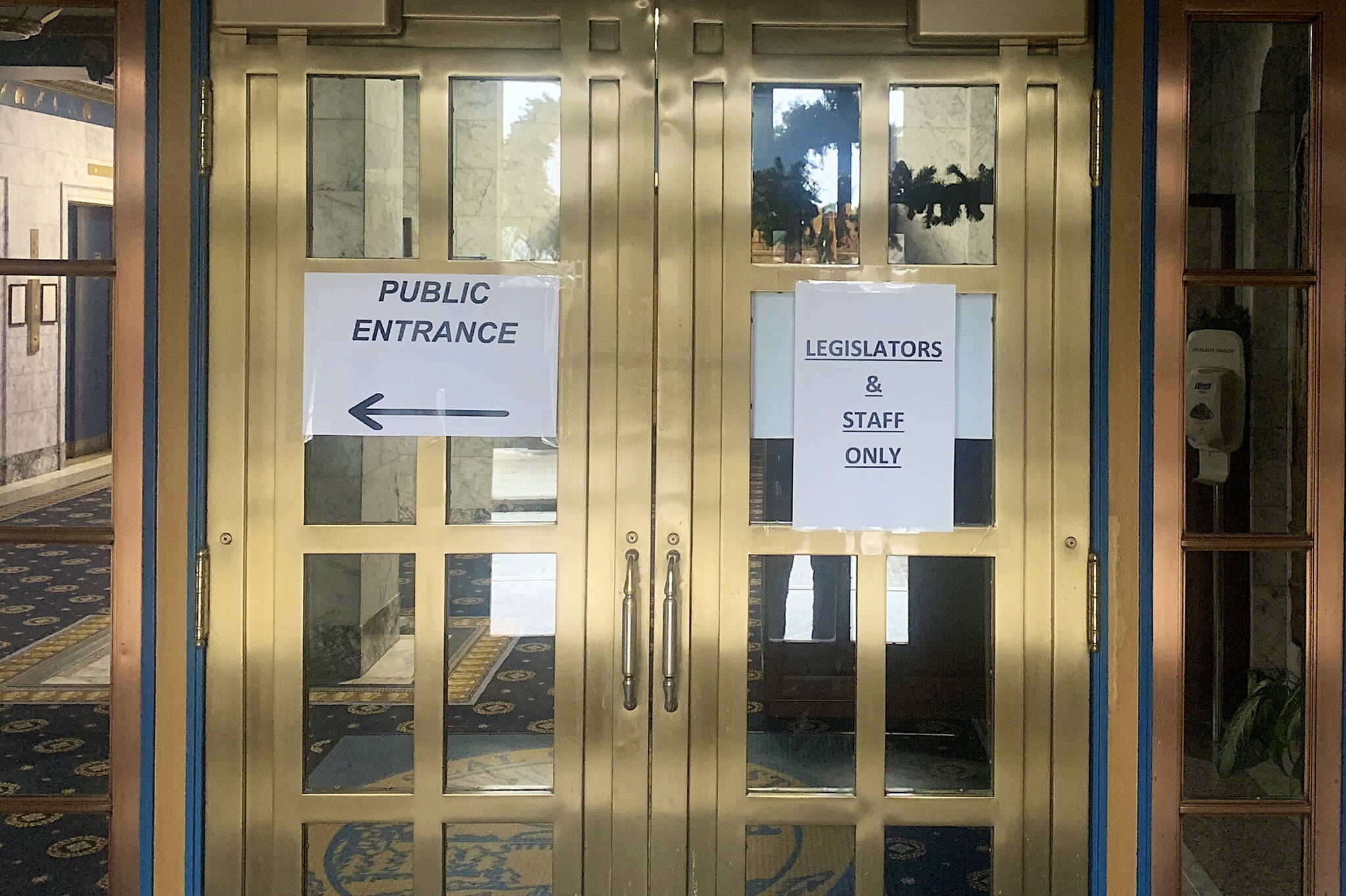 Signs at the front of the Alaska State Capitol on Sunday indicate a designated entrance for legislators and their staff, and direct members of the public to a separate door. (Mark Sabbatini / Juneau Empire)