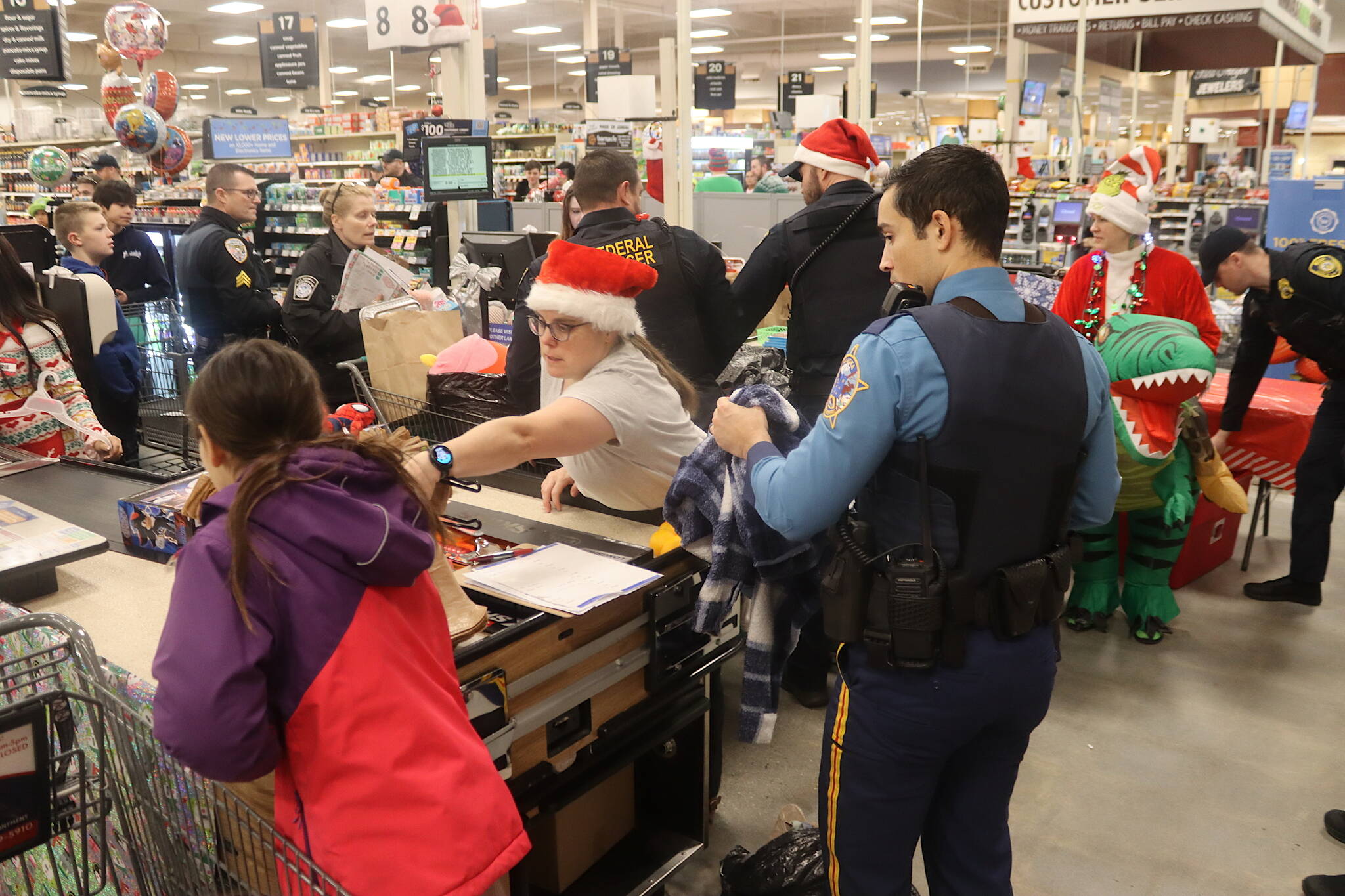 Law enforcement officers from several agencies accompanied by local youths purchase Christmas gifts at Fred Meyer on Saturday during the annual Shop With a Cop event. (Mark Sabbatini / Juneau Empire)