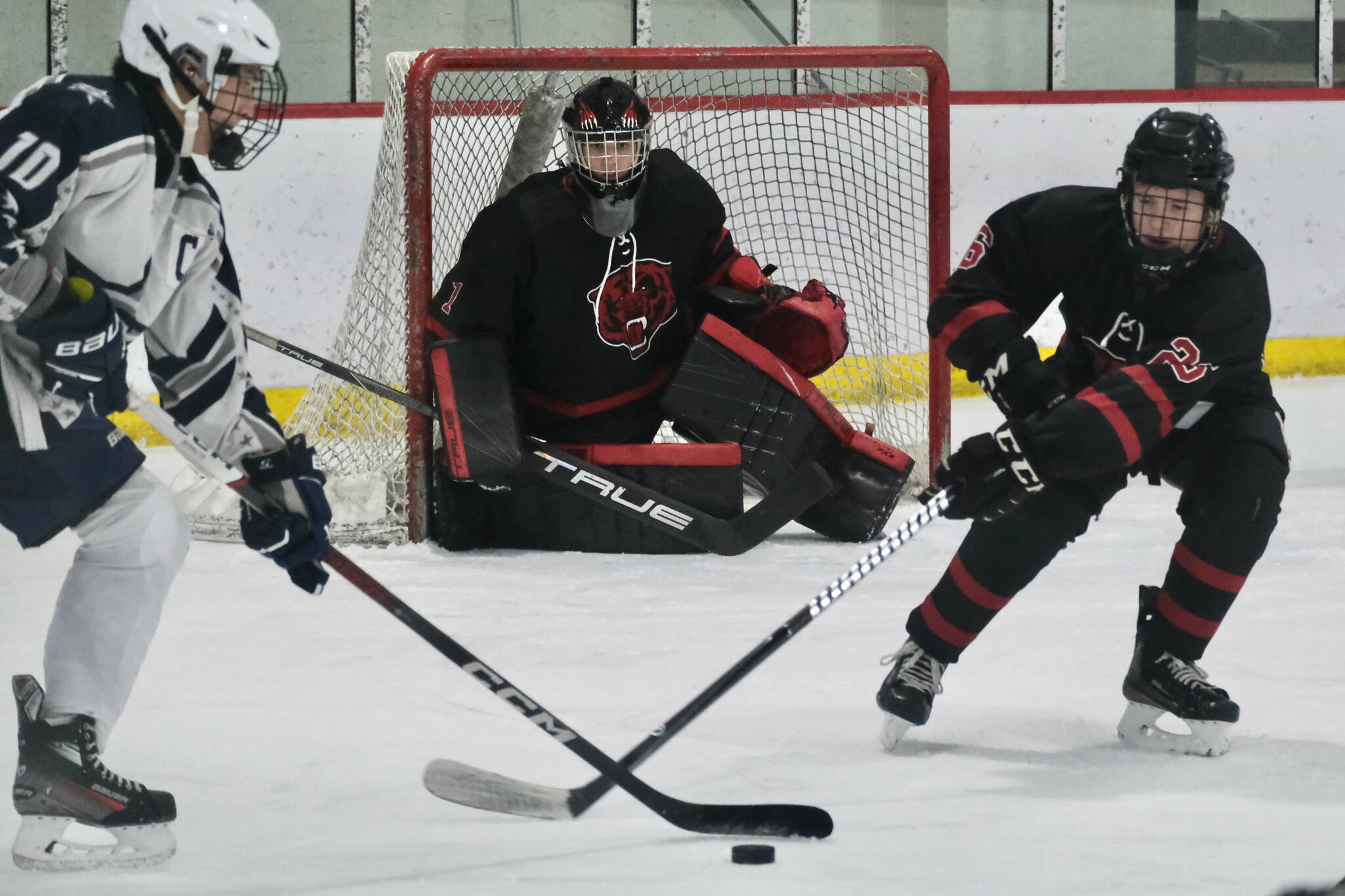 Juneau-Douglas High School: Yadaa.at Kalé senior goalie Caleb Friend (1) controls the net as Soldotna’s Daniel Heath (10) and JDHS senior Loren Platt (26) play a puck during the Crimson Bears 2-0 win over the Stars on Saturday at Treadwell Ice Arena. (Klas Stolpe / Juneau Empire)