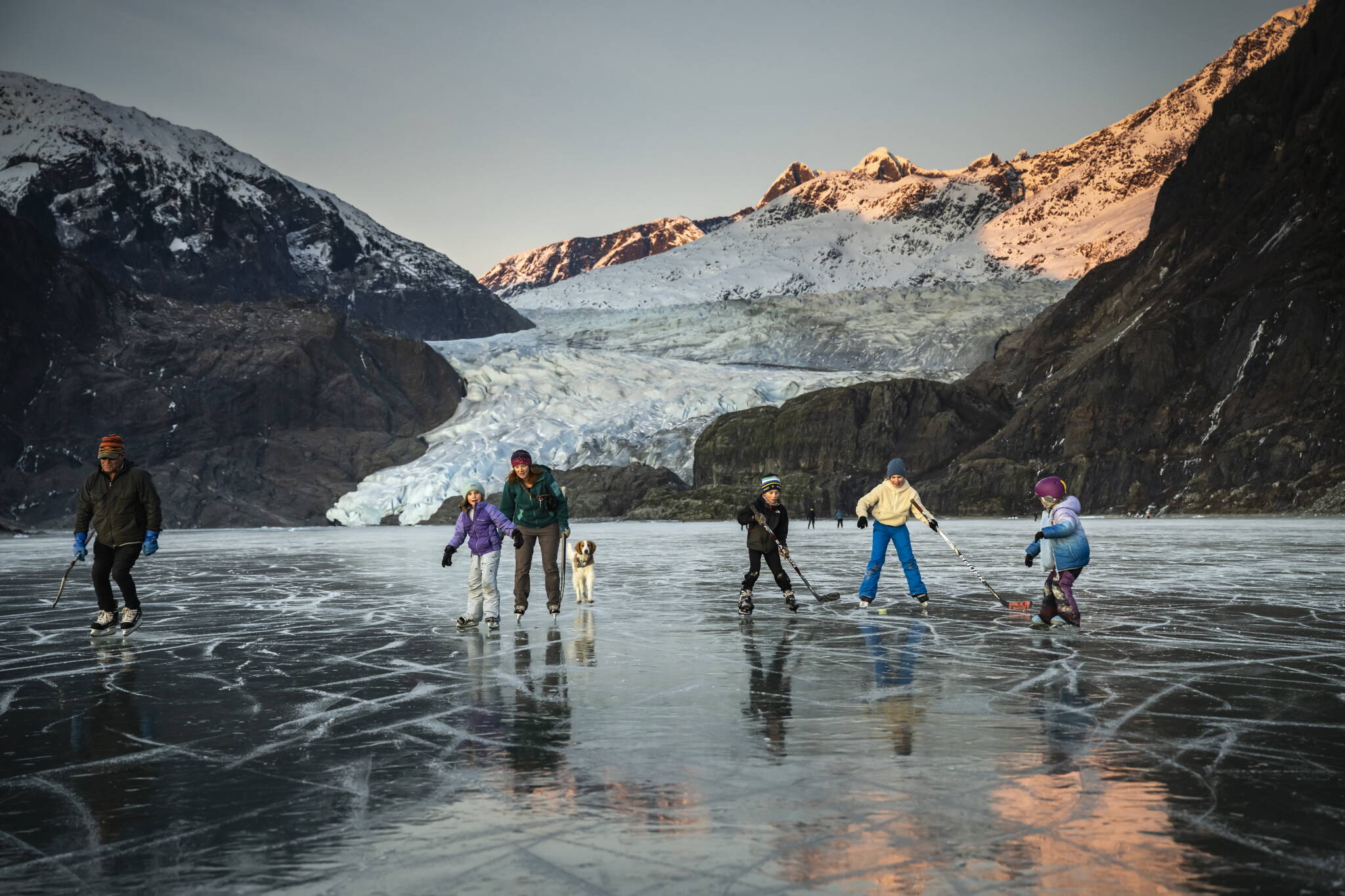 A family ice skates and perfects their hockey prowess on Mendenhall Lake, below Mendenhall Glacier, outside of Juneau, Alaska, Nov. 24, 2024. The state’s capital, a popular cruise port in summer, becomes a bargain-seeker’s base for skiing, skating, hiking and glacier-gazing in the winter off-season. (Christopher S. Miller/The New York Times)