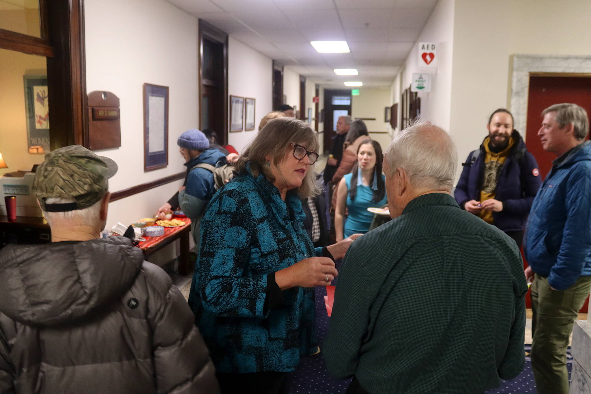 State Rep. Sara Hannan talks with visitors outside her office at the Alaska State Capitol during the annual holiday open house hosted by Juneau’s legislative delegation on Friday. (Mark Sabbatini / Juneau Empire)