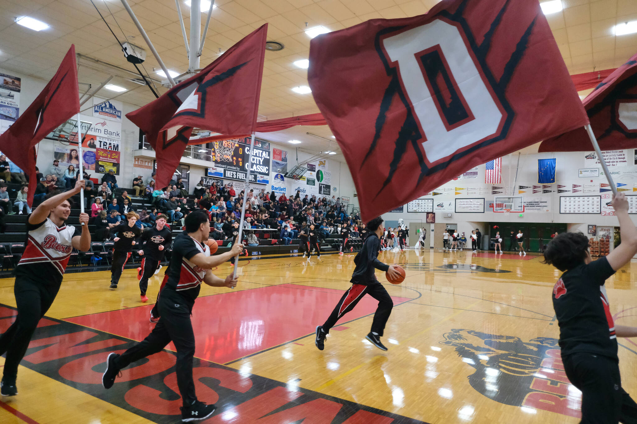 The Juneau-Douglas High School: Yadaa.at Kalé cheer squad leads the Crimson Bears boys onto the floor before their game against Soldotna during Saturday action at the George Houston Capital City Classic in Juneau. (Klas Stolpe / Juneau Empire)