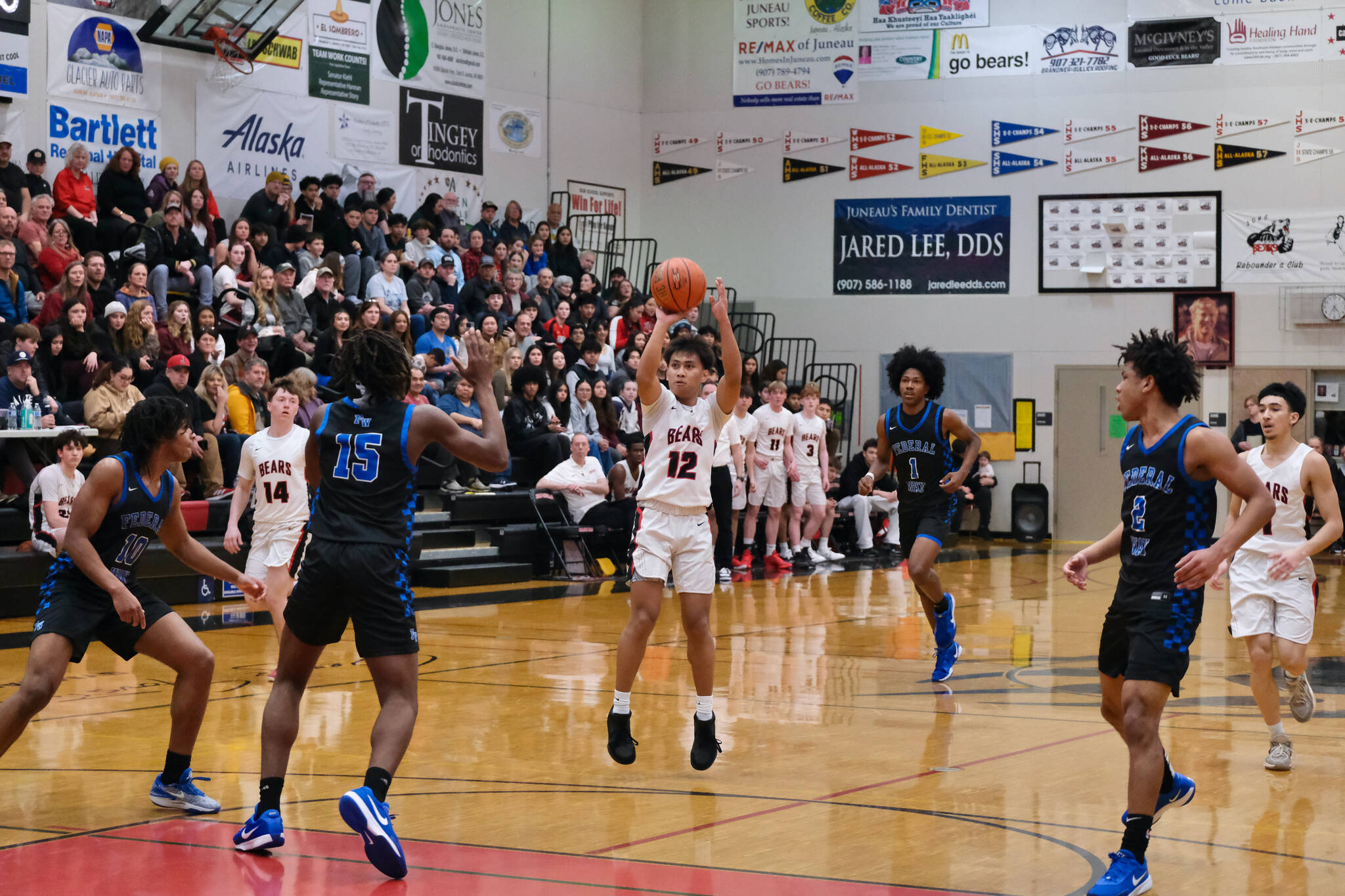 Juneau-Douglas High School: Yadaa.at Kalé junior Joren Gasga (12) shoots a three-pointer as Federal Way seniors Jacob Hurskin (10), Saxon Niles (15) Geron White (1) and Angelo Williams (2) defend during the Crimson Bears 61-48 loss to the Eagles in the boys championship game at the George Houston Capital City Classic on Sunday in Juneau. (Klas Stolpe / Juneau Empire)