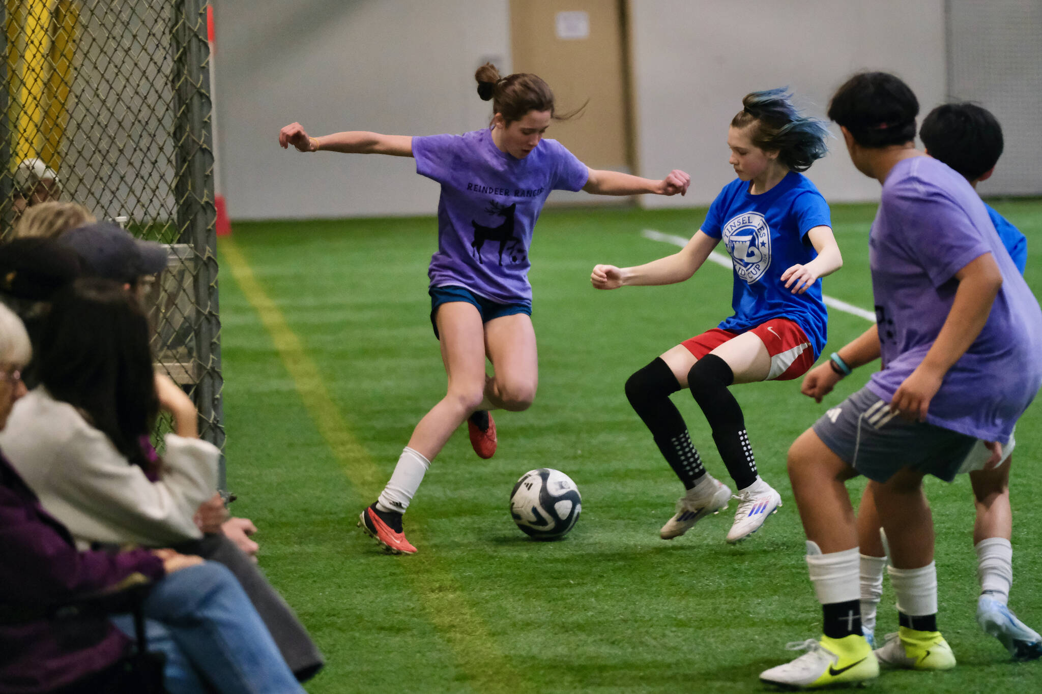 Reindeer Rangers player Maddie Dale and Tinsel Toes player El Lasinski play a ball during the Holiday Cup middle school semifinals Monday at Dimond Park Field House. Finals for all divisions are on Tuesday. (Klas Stolpe / Juneau Empire)