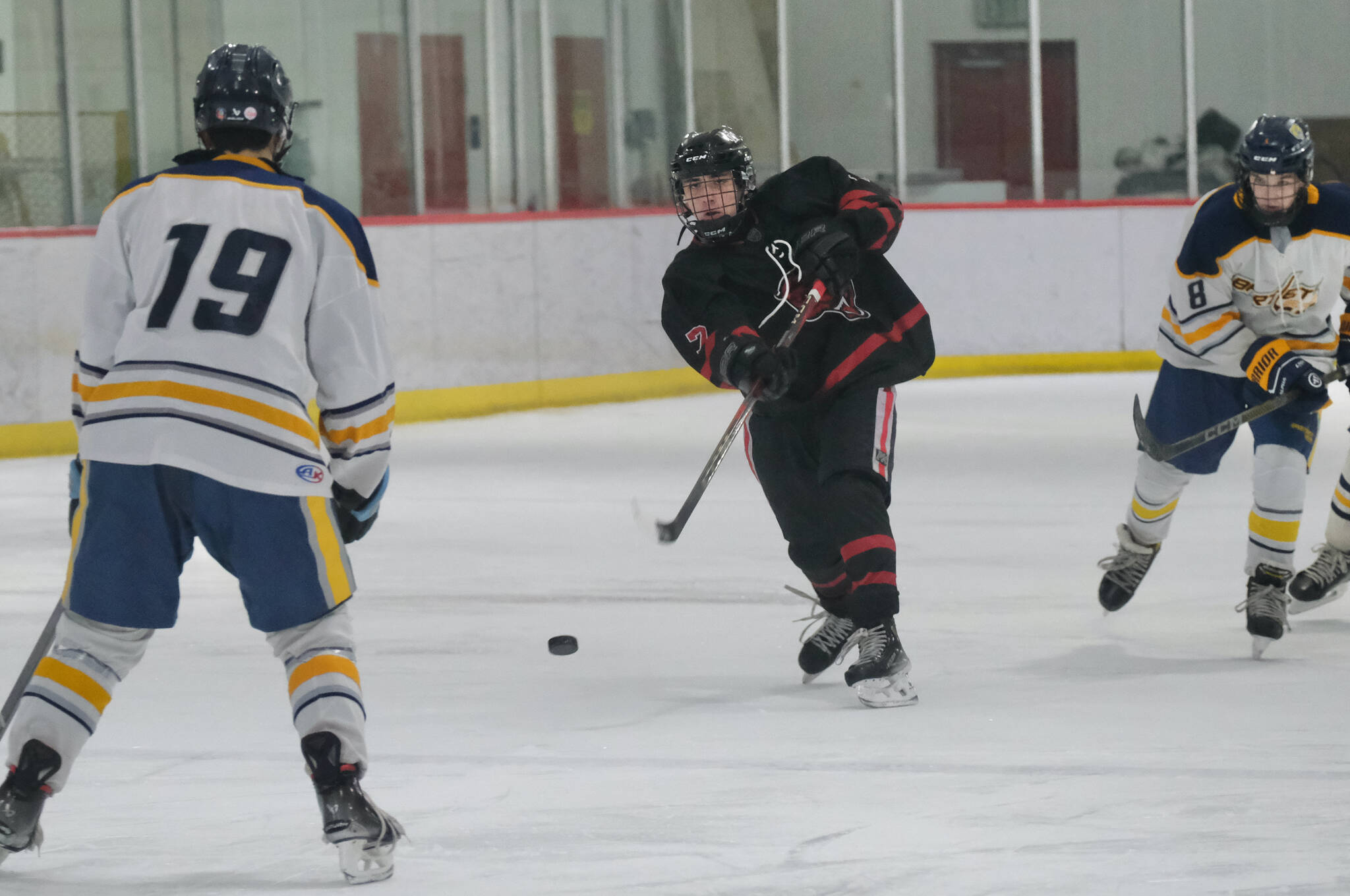 Juneau-Douglas High School: Yadaa.at Kalé junior Paxton Mertl (7) shoots against Bartlett’s Dylan Beals during the Crimson Bears 7-5 win over the Golden Bears on Friday at the Treadwell Ice Arena. The teams play again Saturday at 3 p.m. (Klas Stolpe / Juneau Empire)