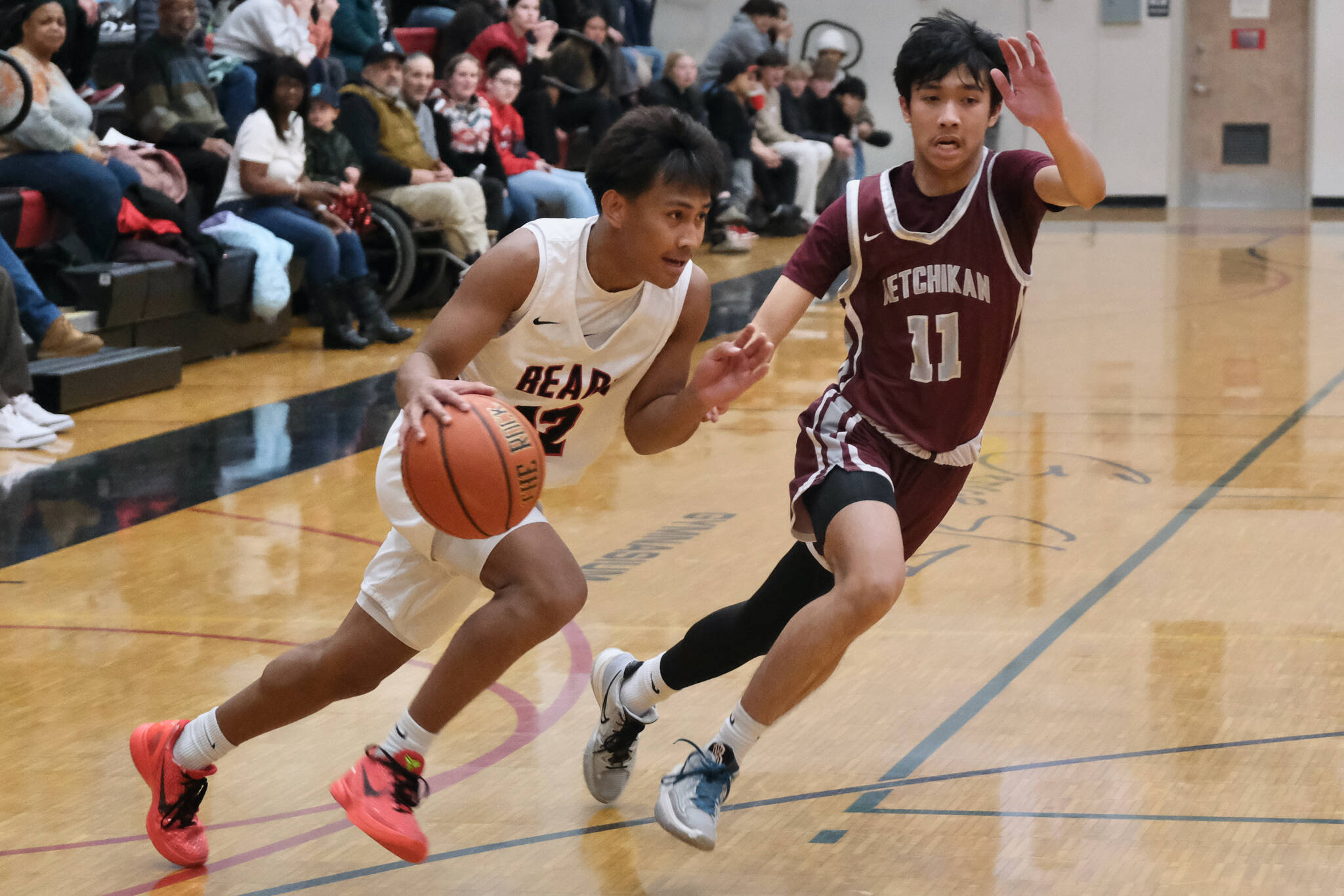 Juneau-Douglas High School: Yadaa.at Kalé junior Joren Gasga (12) dribbles past Ketchikan junior Jozaiah Dela Cruz (11) during the Crimson Bears 52-48 loss to the kings on Friday at the George Houston Gymnasium in Juneau. (Klas Stolpe / Juneau Empire)