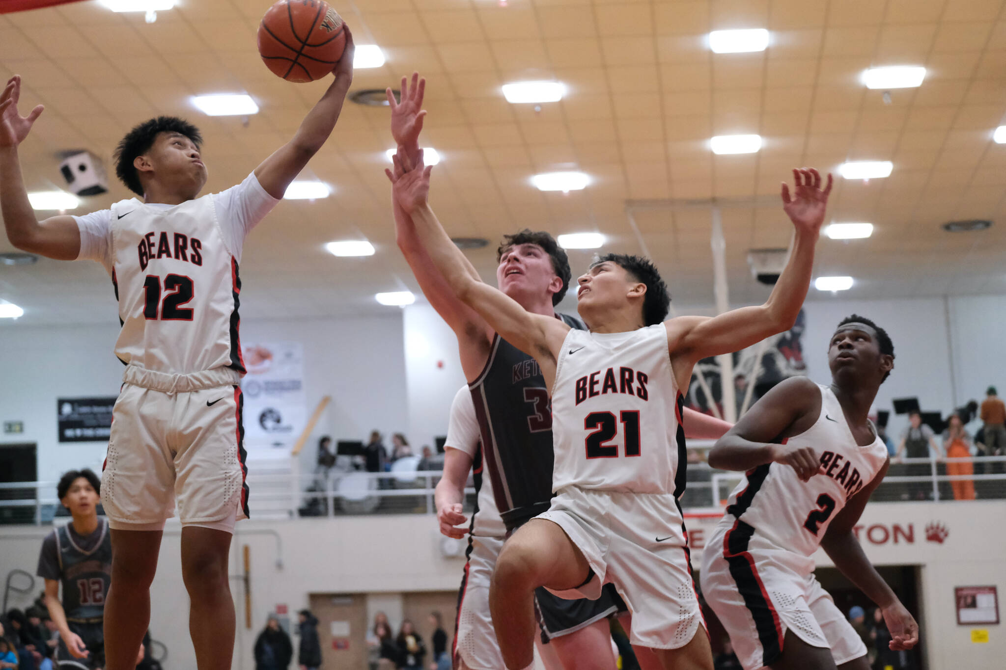 Juneau-Douglas High School: Yadaa.at Kalé juniors Joren Gasga (12) and Tyler Frisby (21) and senior Ahmir Parker (2) rebound with Ketchikan senior Marcus Stockhausen during the Crimson Bears’ 70-63 loss to the Kings on Saturday at the George Houston Gymnasium in Juneau. (Klas Stolpe / Juneau Empire)