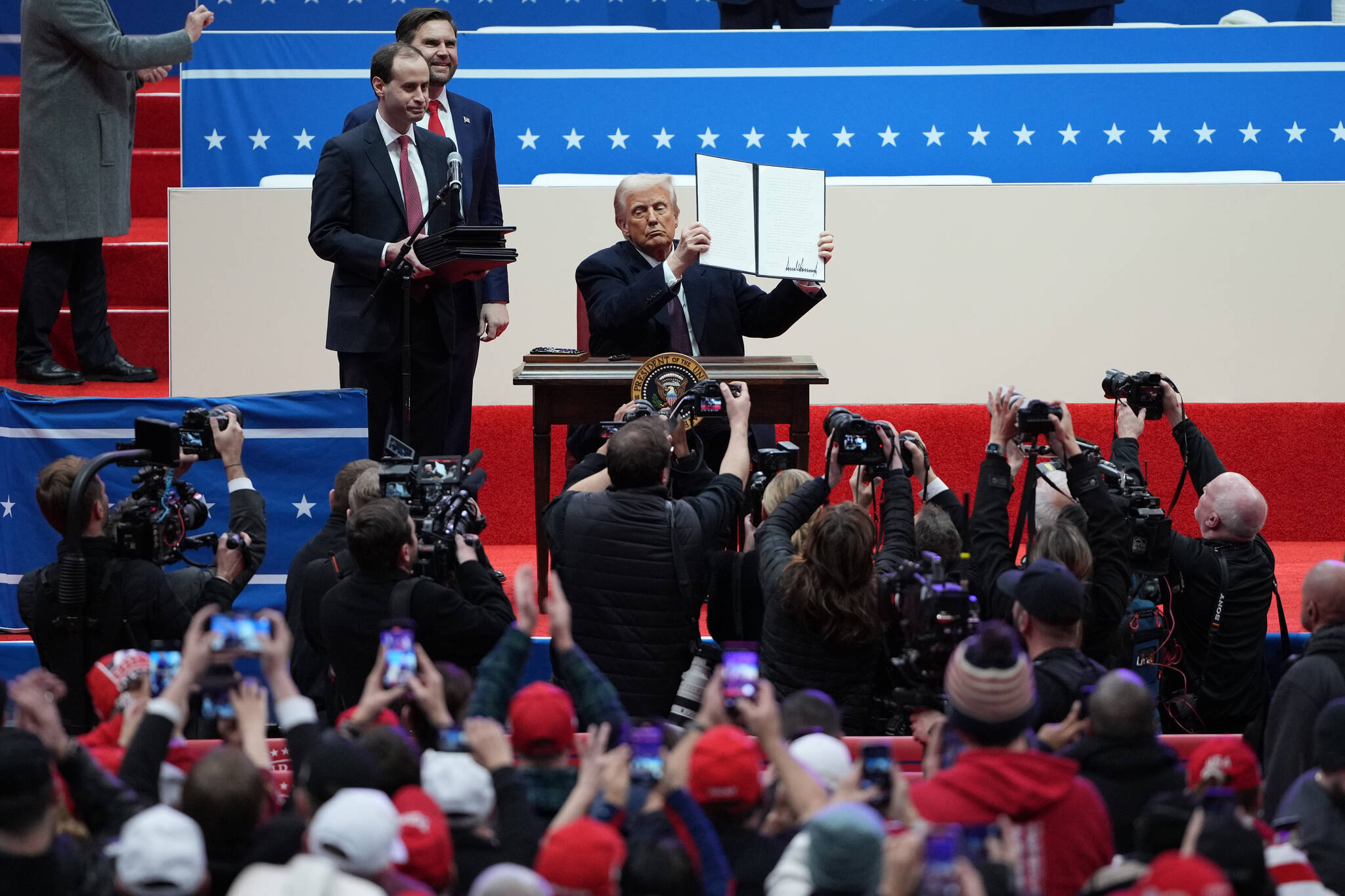 President Donald Trump holds up an executive order after signing it on stage during the inaugural parade inside Capitol One Arena following his inauguration as the 47th president in Washington, Jan. 20, 2025. (Eric Lee/The New York Times)