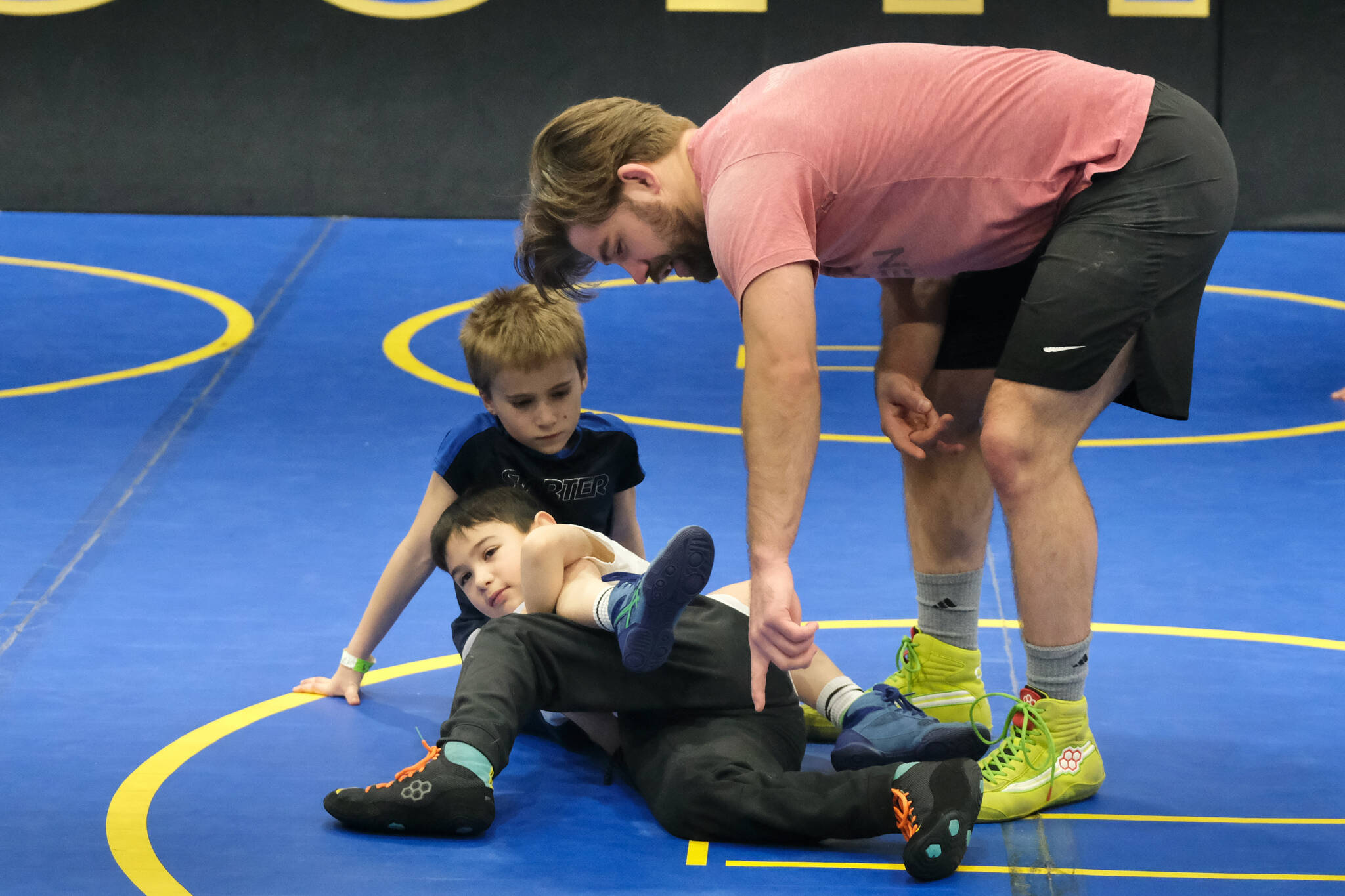 Askren Wrestling Academy coach Wilder Wichman helps Garrett Reid and Rylan Pegues learn a technique on Monday during a three-day wrestling clinic at the Juneau Wrestling Center. (Klas Stolpe / Juneau Empire)