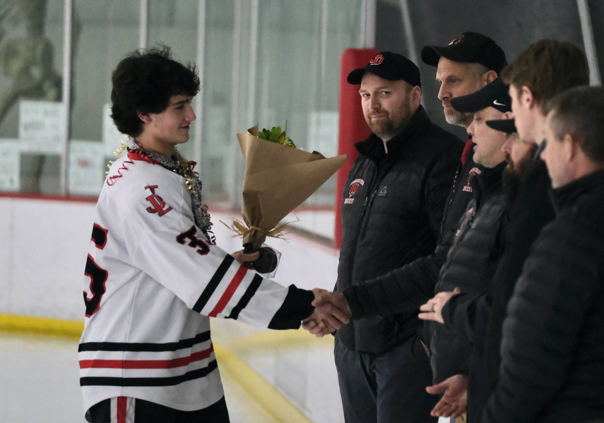 Juneau-Douglas High School: Yadaa.at Kalé senior Dylan Sowa shakes hands with coaches during ceremonies before the Crimson Bears’ game Friday against the visiting Kenai Kardinals at Treadwell Ice Arena. (Klas Stolpe / Juneau Empire)