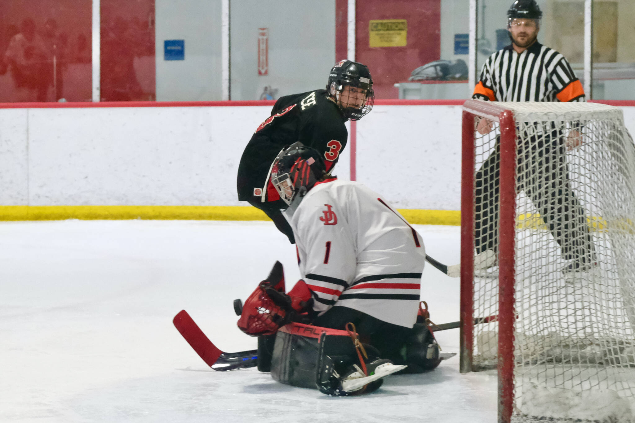 Juneau-Douglas High School: Yadaa.at Kalé senior goalie Caleb Friend (1) stops a shot by Kenai senior Logan Mese (3) during the Crimson Bears’ 5-1 loss to the Kardinals on Saturday at Treadwell Ice Arena. (Klas Stolpe / Juneau Empire)