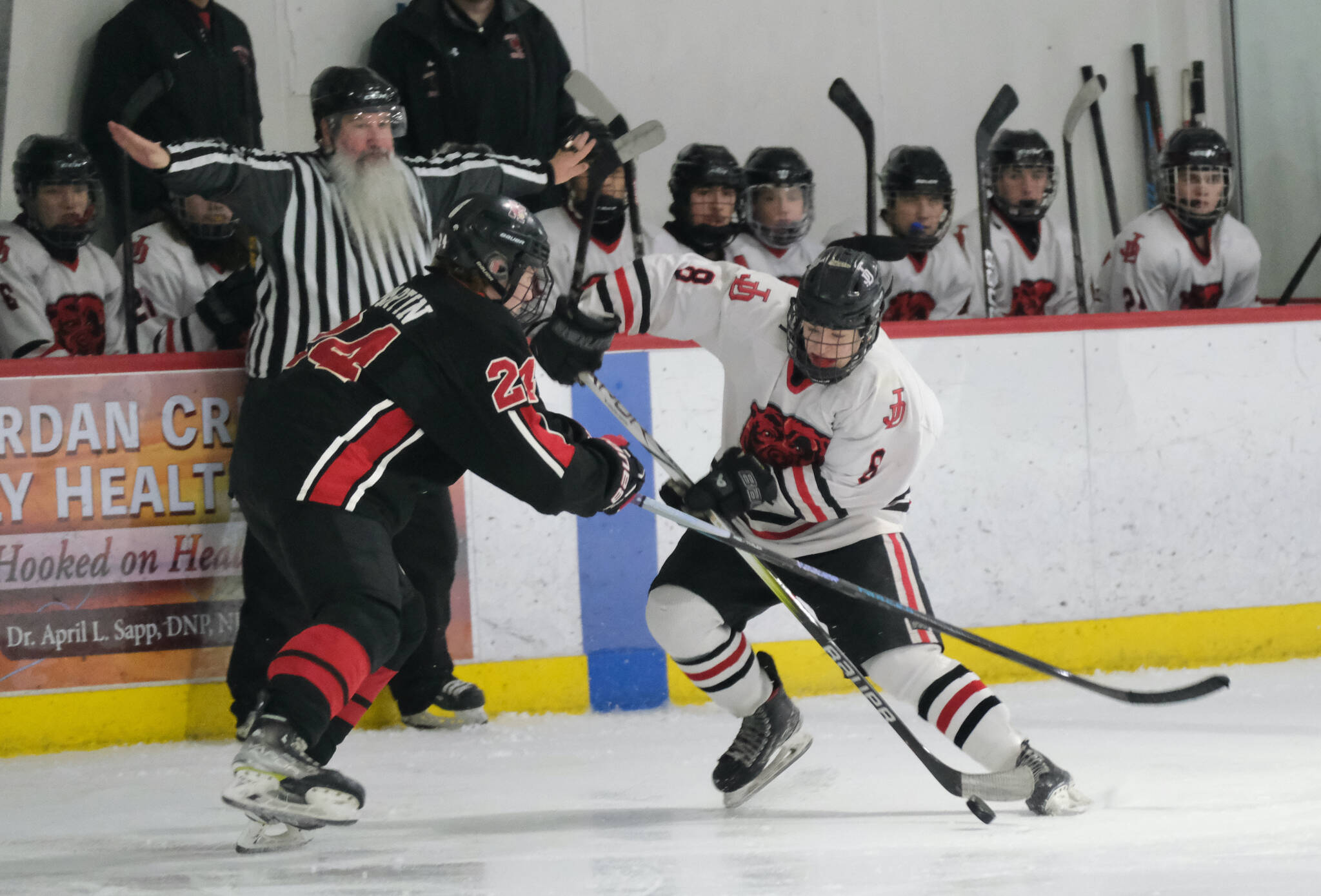 Juneau-Douglas High School: Yadaa.at Kalé senior Zander Smith (8) moves a puck against Kenai’s Avery Martin (24) during the Crimson Bears’ 5-1 loss to the Kardinals on Saturday at Treadwell Ice Arena. (Klas Stolpe / Juneau Empire)