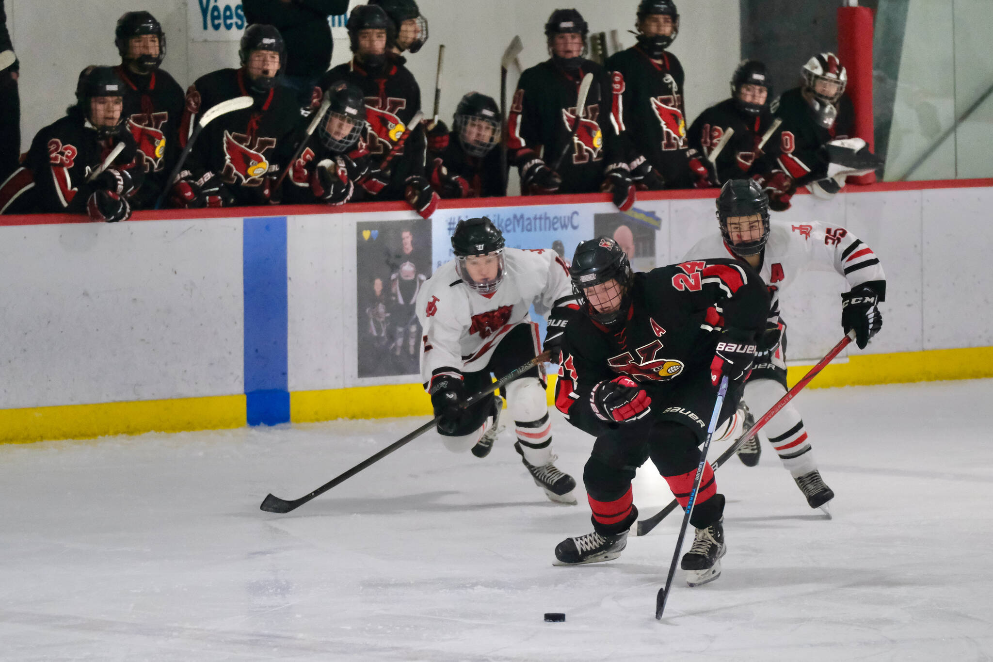 Juneau-Douglas High School: Yadaa.at Kalé junior Emerson Newell (12) and senior Dylan Sowa (35) chase Kenai’s Avery Martin (24) during the Crimson Bears’ 5-1 loss to the Kardinals on Saturday at Treadwell Ice Arena. (Klas Stolpe / Juneau Empire)