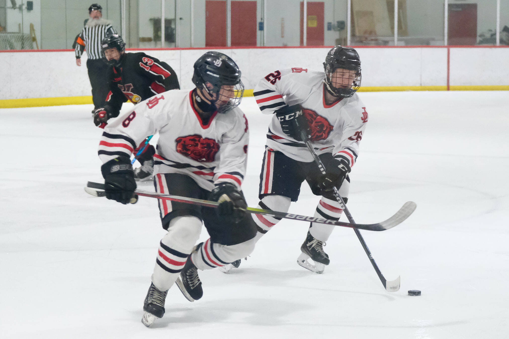 Juneau-Douglas High School: Yadaa.at Kalé seniors Zander Smith (8) and Loren Platt (26) control a puck during the Crimson Bears’ 5-4 loss to the Kardinals on Friday at Treadwell Ice Arena. The teams play Saturday at 8:30 a.m. (Klas Stolpe / Juneau Empire)