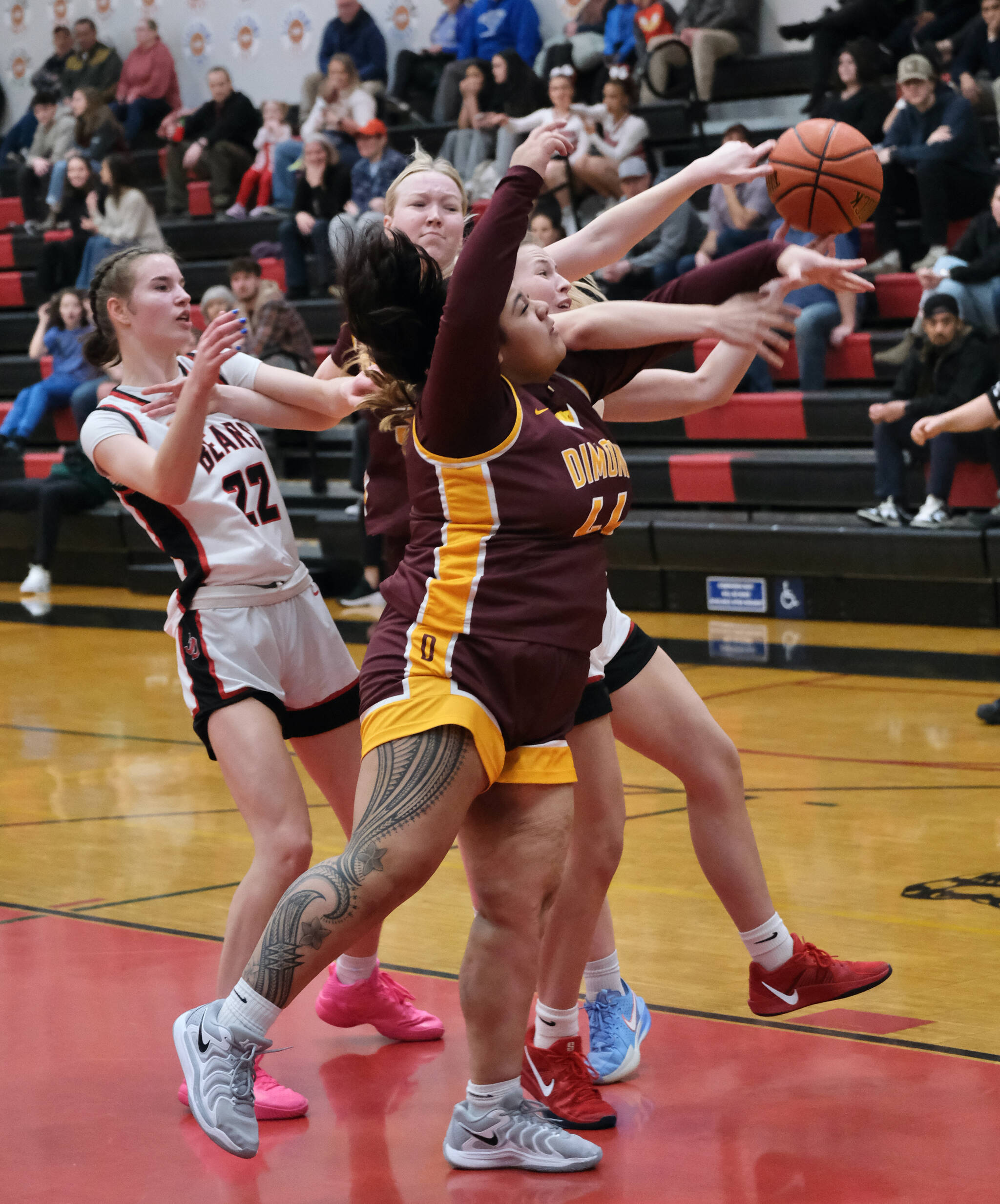 Juneau-Douglas High School: Yadaa.at Kalé seniors Kerra Baxter (22) and Addison Wilson battle for a rebound with Dimond senior Evan Hamey and sophomore Noelani Vanilau (44) during the Crimson Bears 53-43 loss to the Lynx on Saturday in the George Houston Gymnasium. (Klas Stolpe / Juneau Empire)