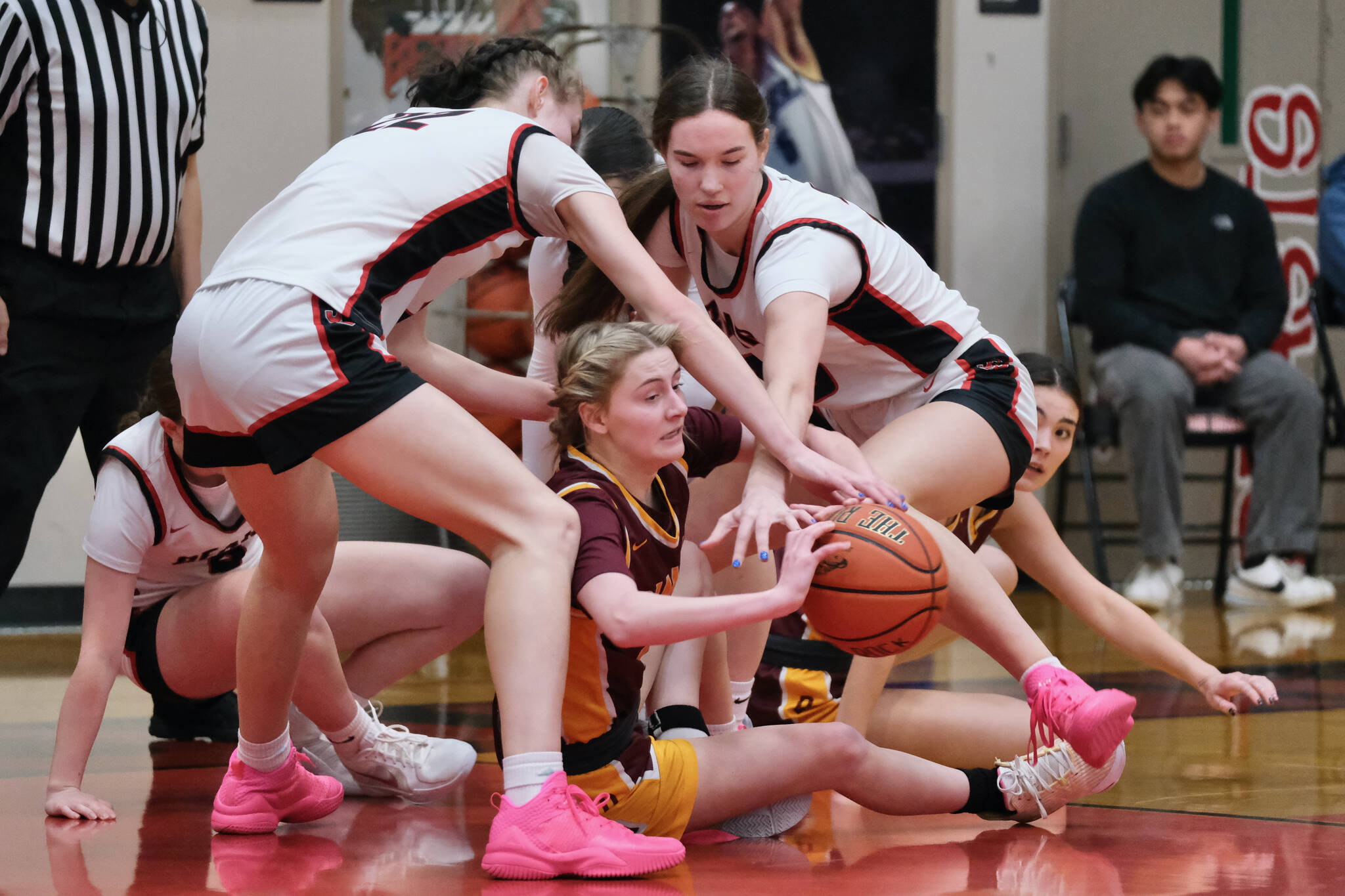 Dimond junior Katie MacDonald and Juneau-Douglas High School: Yadaa.at Kalé seniors Kerra and Cailynn Baxter work for a loose ball Saturday during the Lynx’ 53-43 win over the Crimson Bears in the George Houston Gymnasium. (Klas Stolpe / Juneau Empire)