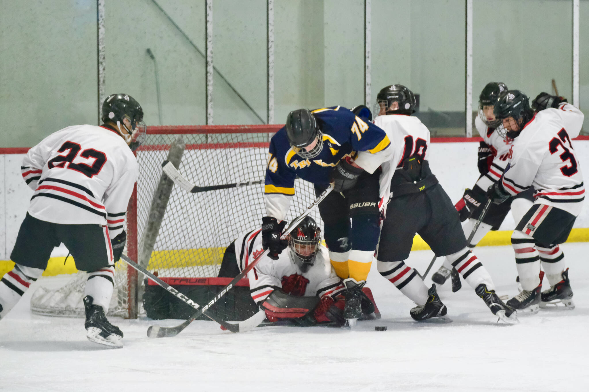 Juneau-Douglas High School: Yadaa.at Kalé senior Matthew Plang (22), senior goalie Caleb Friend (1), Tri-Valley's Owen Jusczak (74), JDHS junior Elias Schane (10), JDHS sophomore Bryden Roberts (40) and JDHS senior Emilio Holbrook (37) converge on a puck near the Crimson Bears net during Friday's 8-3 JDHS win over the Warriors at Treadwell Ice Arena. (Klas Stolpe / Juneau Empire)