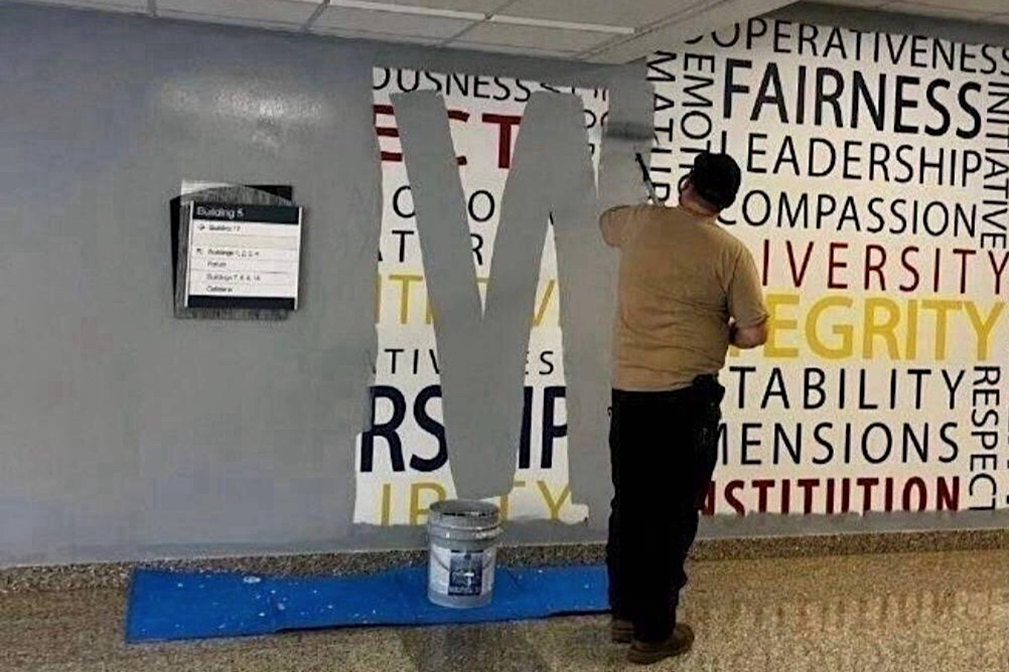 A worker paints over a wall mural featuring words such as “fairness,” “leadership,” “compassion,” “diversity” and “integrity” at the FBI Academy at Quantico on Wednesday. (Anonymous photo provided to The New York Times)