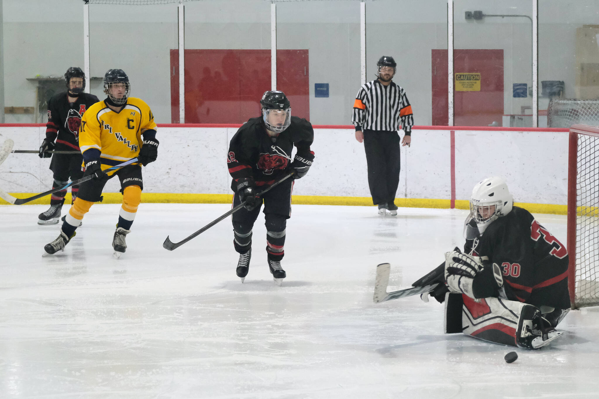 Juneau-Douglas High School: Yadaa.at Kalé sophomore goalie Taylor Petrie (30) deflects a Tri-Valley shot during the Crimson Bears’ 4-2 loss to the Warriors at Treadwell Ice Arena on Saturday. (Klas Stolpe / Juneau Empire)