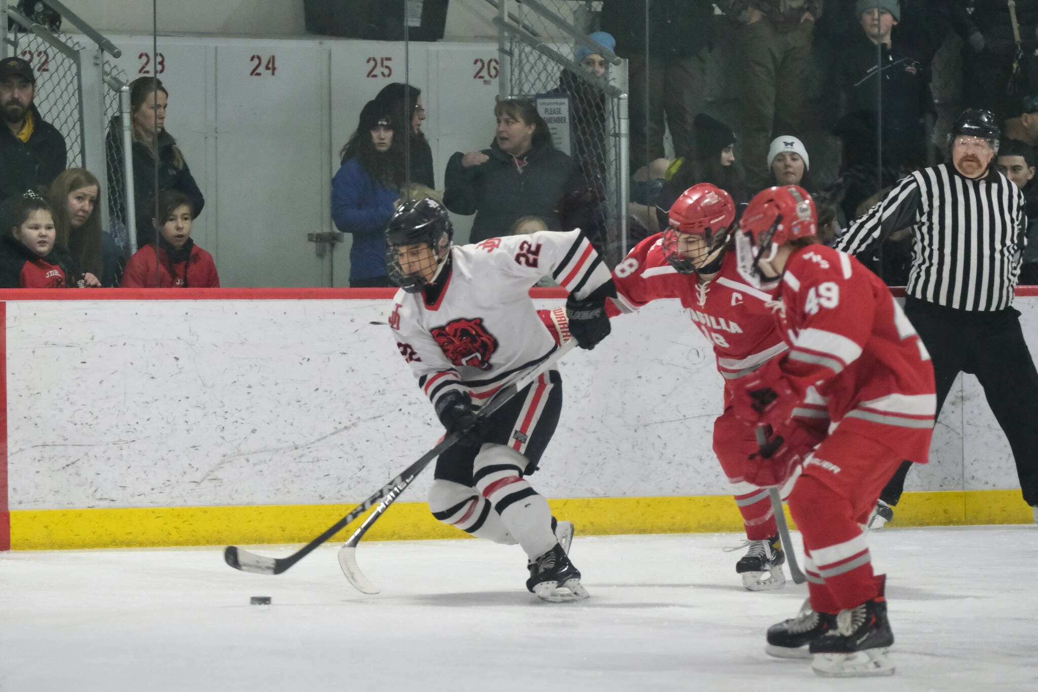 Juneau-Douglas High School: Yadaa.at Kalé senior Matthew Plang (22) skates away from Wasilla senior Karson McGrew (18) and freshman Dylan Mead (49) during the Crimson Bears’ 3-1 win over the Warriors at Treadwell Ice Arena on Saturday. (Klas Stolpe / Juneau Empire)