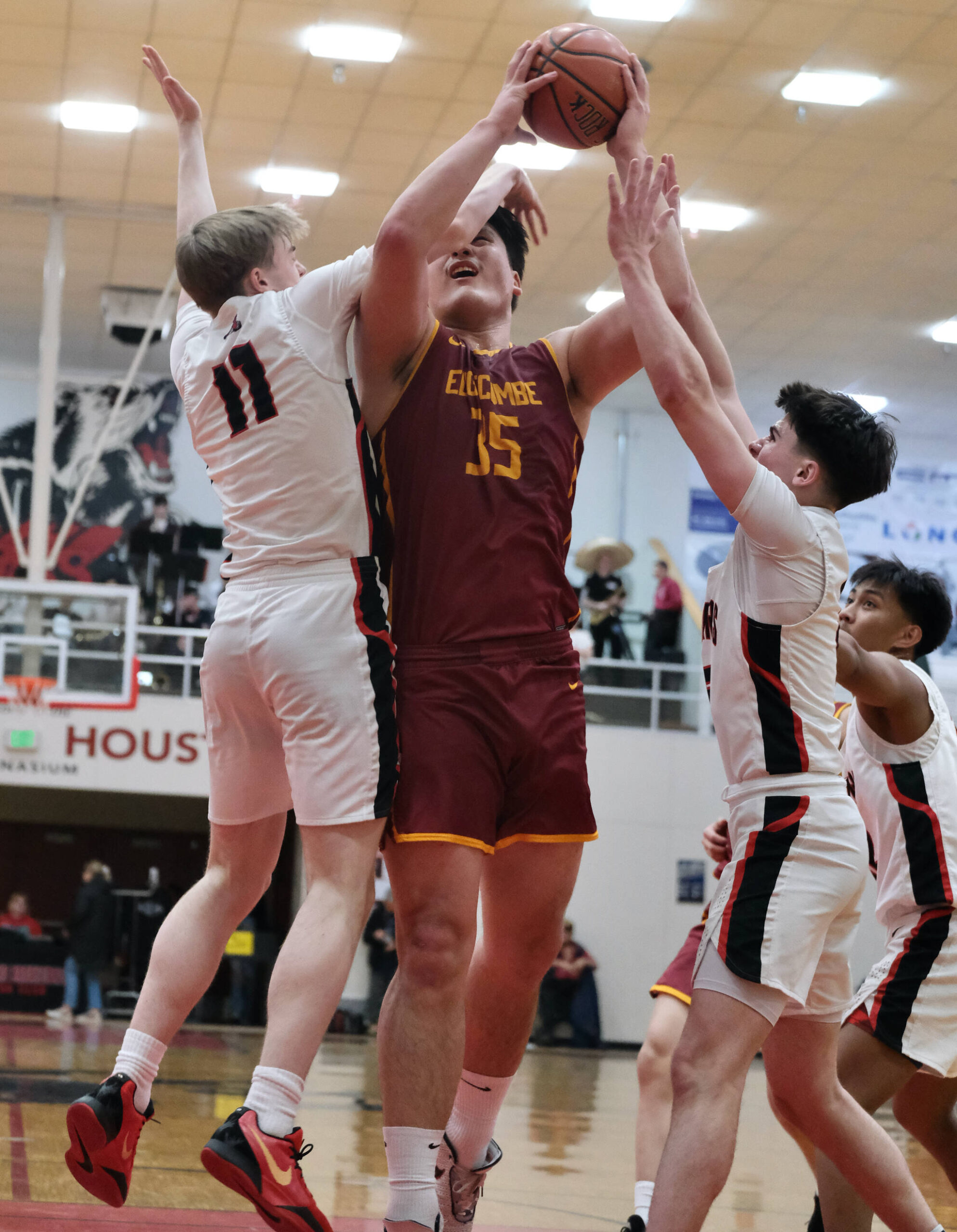 Mt. Edgecumbe senior Donovan Stephen-Standifer (35) is defended by Juneau-Douglas High School: Yadaa.at Kalé senior Ben Sikes (11) and juniors Brandon Casperson and Joren Gasga during the Braves’ 68-47 win over the Crimson Bears on Saturday in the George Houston Gymnasium. (Klas Stolpe / Juneau Empire)