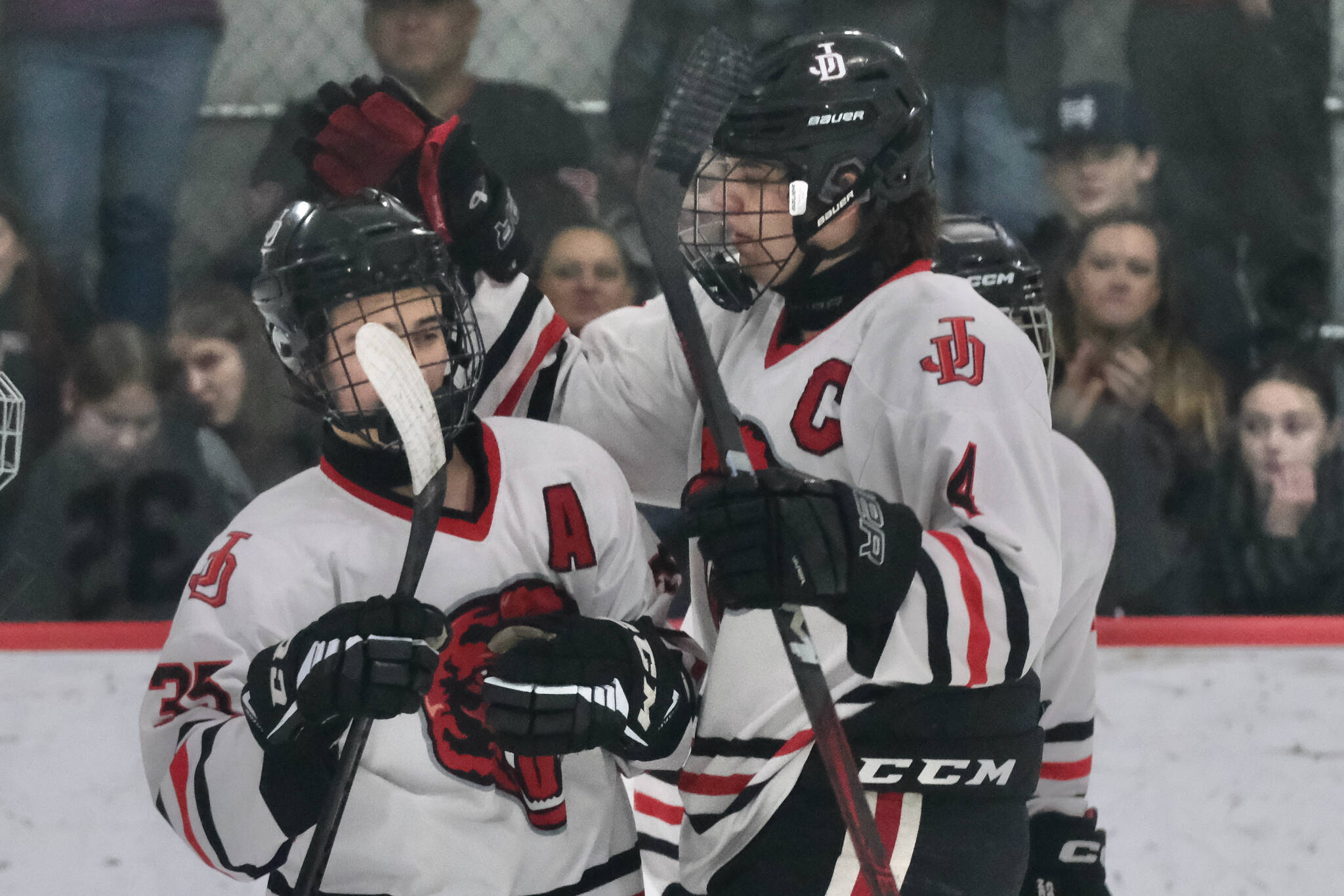 In this file photo Juneau-Douglas High School: Yadaa.at Kalé senior Dylan Sowa (35) is congratulated on a scoring goal by senior captain Luke Bovitz (4) during senior night weekend against Kenai. Sowa had two goals Friday in the Crimson Bears’ 5-2 loss to Palmer at the 2025 ASAA Division II Hockey State Tournament in Soldotna. JDHS will face Kenai in the 3rd/5th-place game Saturday. (Klas Stolpe / Juneau Empire)