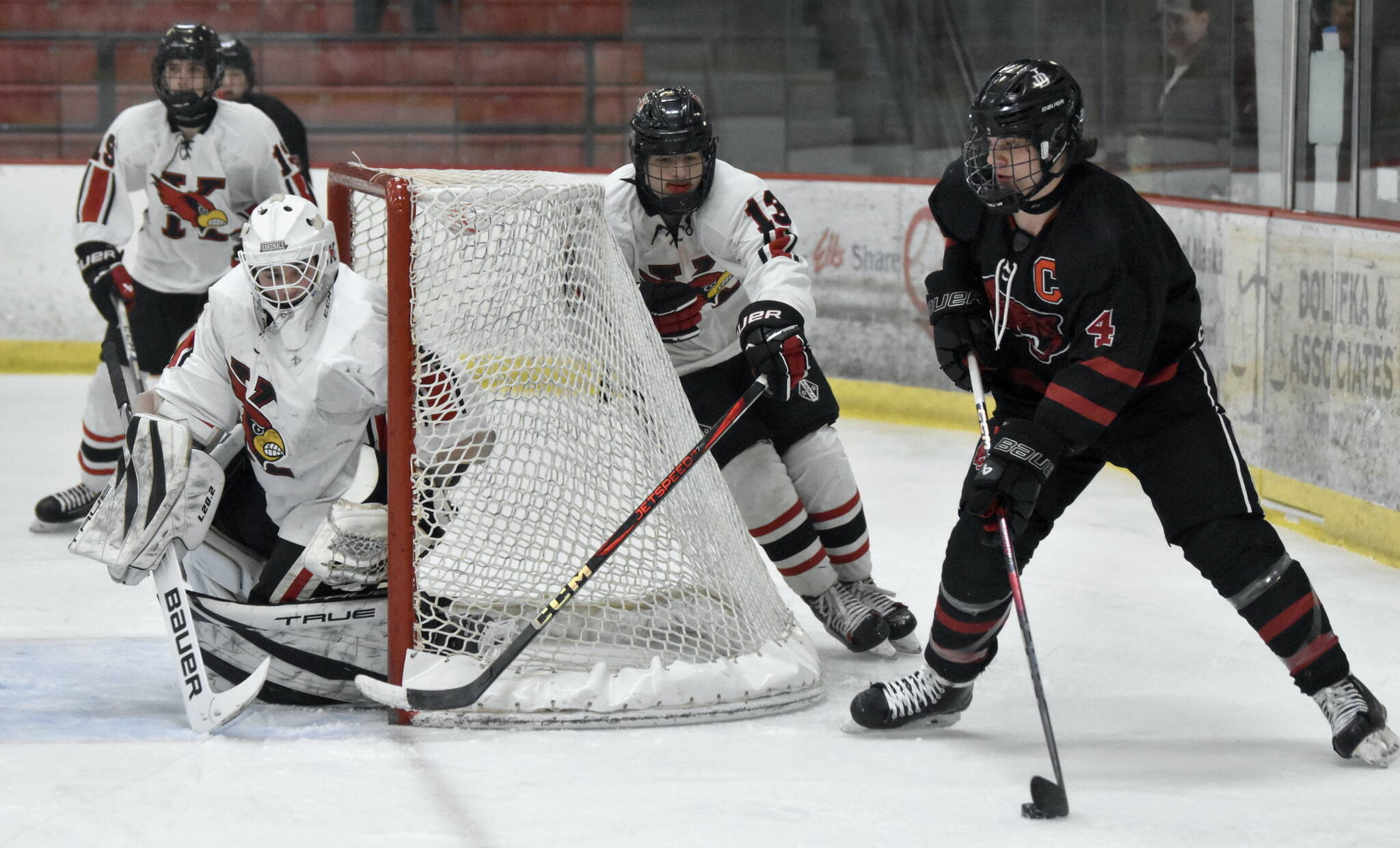 Lucas Bovitz of Juneau-Douglas: Yadaa.at Kale carries the puck with attention from Kenai Central goalie Evyn Witt and William Howard at the First National Cup Division II state hockey tournament Saturday at the Soldotna Regional Sports Complex in Soldotna. (Jeff Helminiak/Peninsula Clarion)