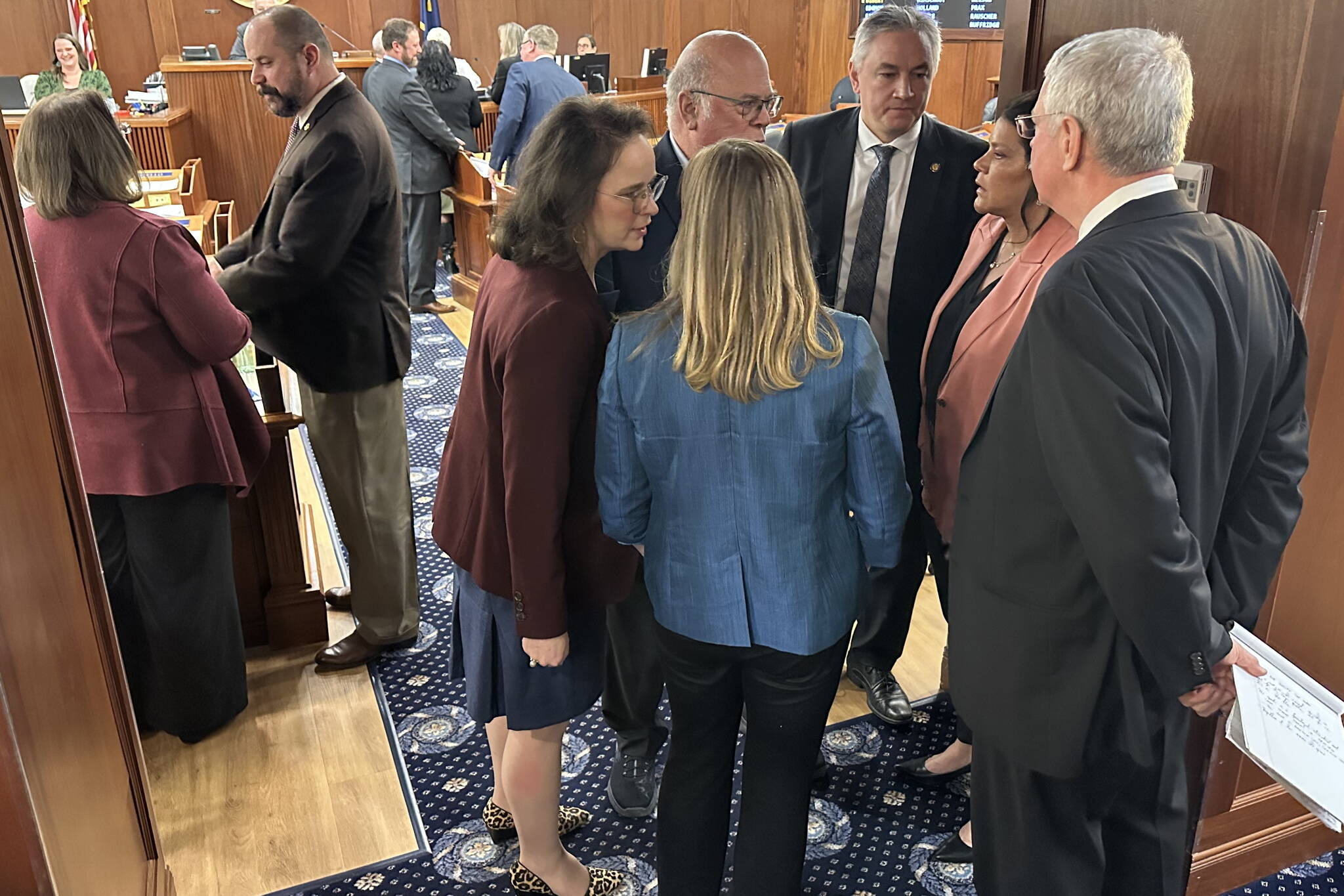 Alaska State House members confer about a proposal to advance an education funding bill during a break in Wednesday’s floor session. (Mark Sabbatini / Juneau Empire)