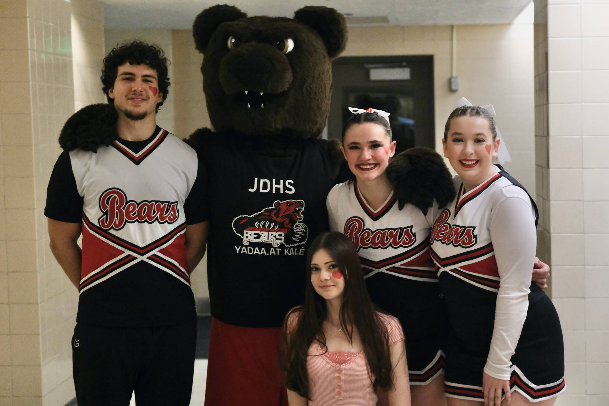 Juneau-Douglas High School: Yadaa.at Kalé cheerleaders Stefano Rivera, MAC the Bear, Olivia Hickman (kneeling), Ayla Keller and Gabby Ely pose for a photo during a recent basketball game at the George Houston Gymnasium. The cheerleaders will be helping honor their seniors and the seniors of the basketball and dance teams and pep band this weekend during homecoming games against North Pole. (Klas Stolpe / Juneau Empire)