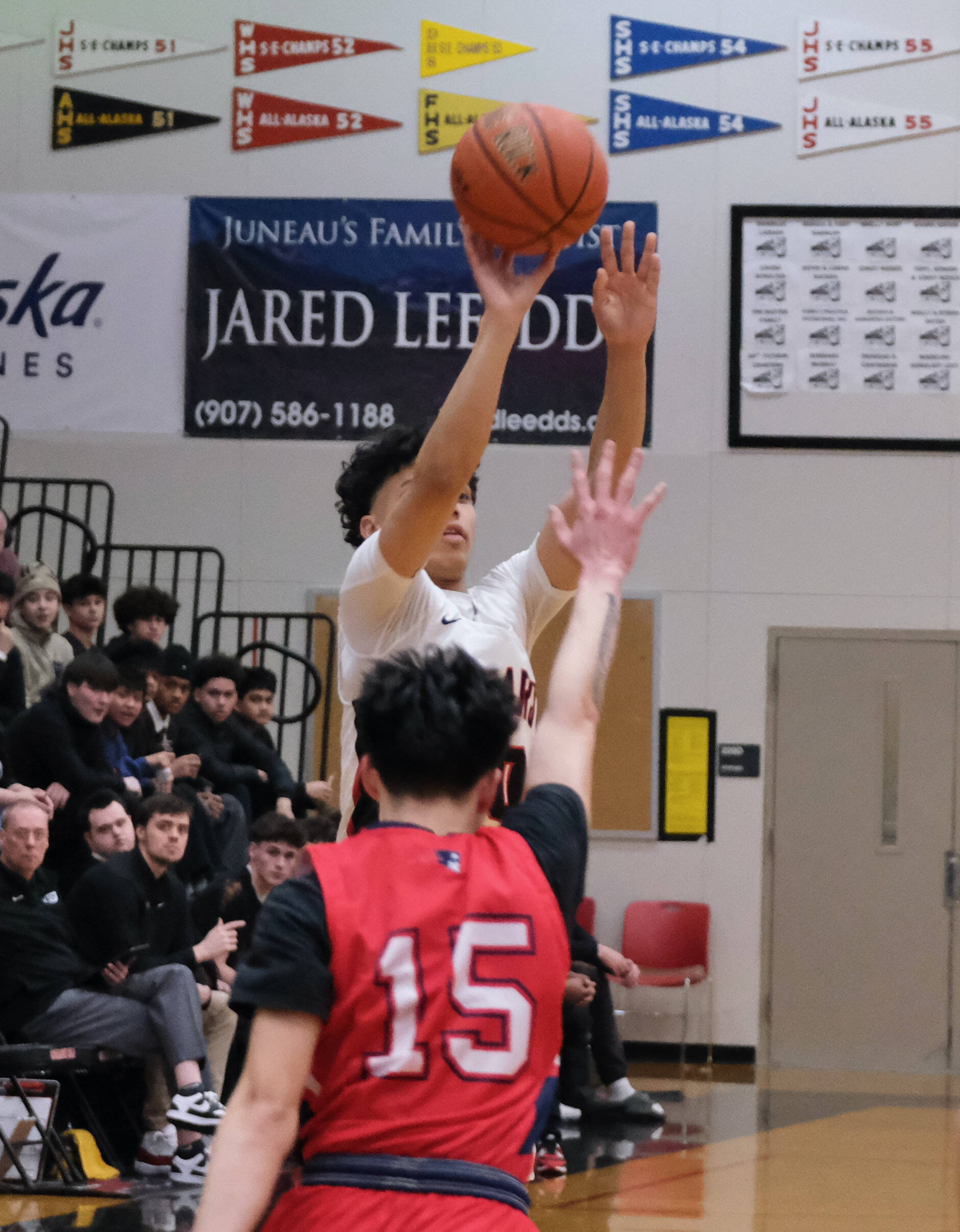 Juneau-Douglas High School: Yadaa.at Kalé senior Pedrin Saceda-Hurt hits a shot past the arc over North Pole senior Nico Mesa (15) during Senior Night honors Saturday at George Houston Gymnasium. (Klas Stolpe / Juneau Empire)