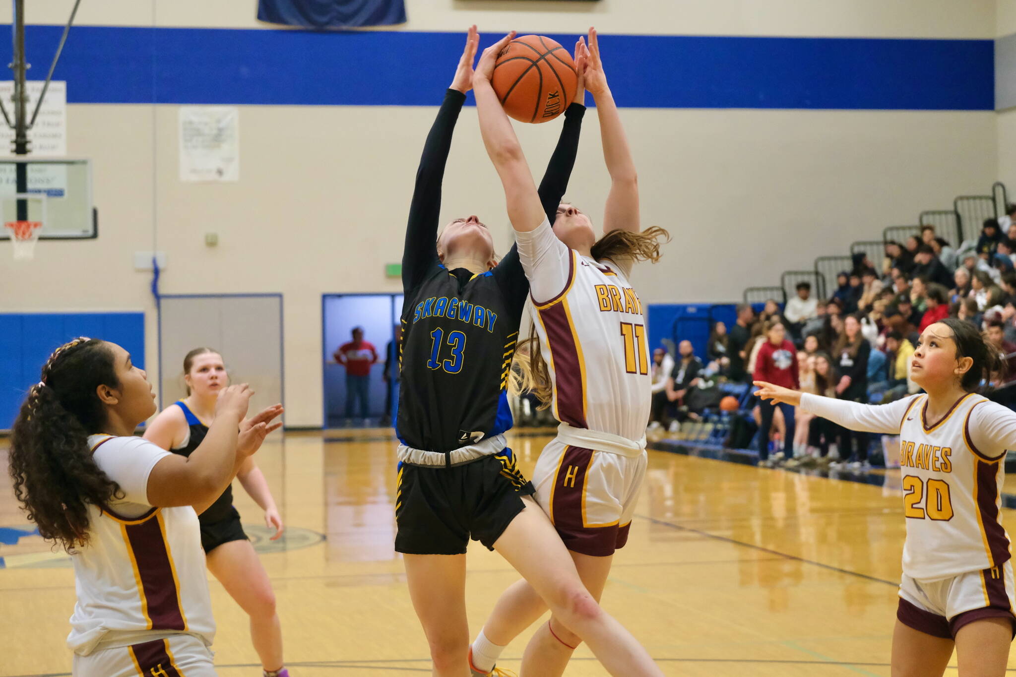 Skagway senior Kaitlyn Tronrud (13) and Hoonah junior Easton Ross (11) rebound during Saturday’s Region V 1A Girls Runner-Up game at Thunder Mountain Middle School. Hoonah won 31-19 for the second berth to state in Anchorage. Klawock won the championship berth Friday. (Klas Stolpe / Juneau Empire)