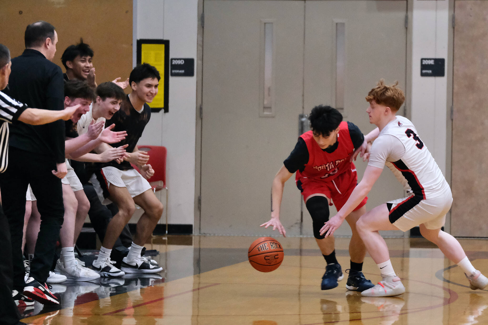 Juneau-Douglas High School: Yadaa.at Kalé senior Gavin Gerrin (3) defends a North Pole player in front of the JDHS bench last weekend. The Crimson Bears boys open the 2A/4A Region V tournament against Kayhi at 7:45 p.m. Thursday in Ketchikan's Clarke Cochran Gymnasium. (Klas Stolpe / Juneau Empire)